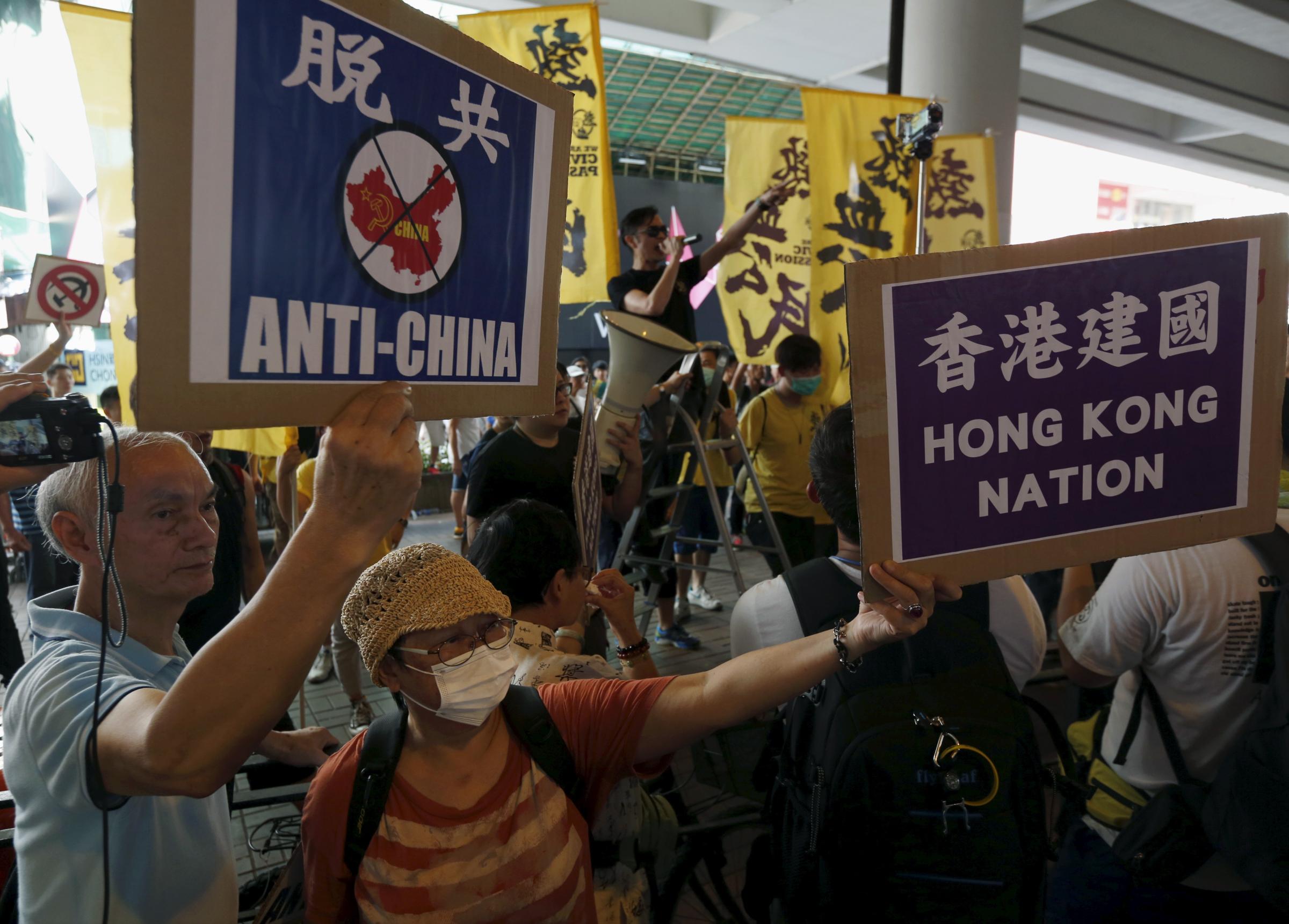 Protesters hold up placards as others shout against pro-China supporters (not in picture) during a demonstration in Hong Kong