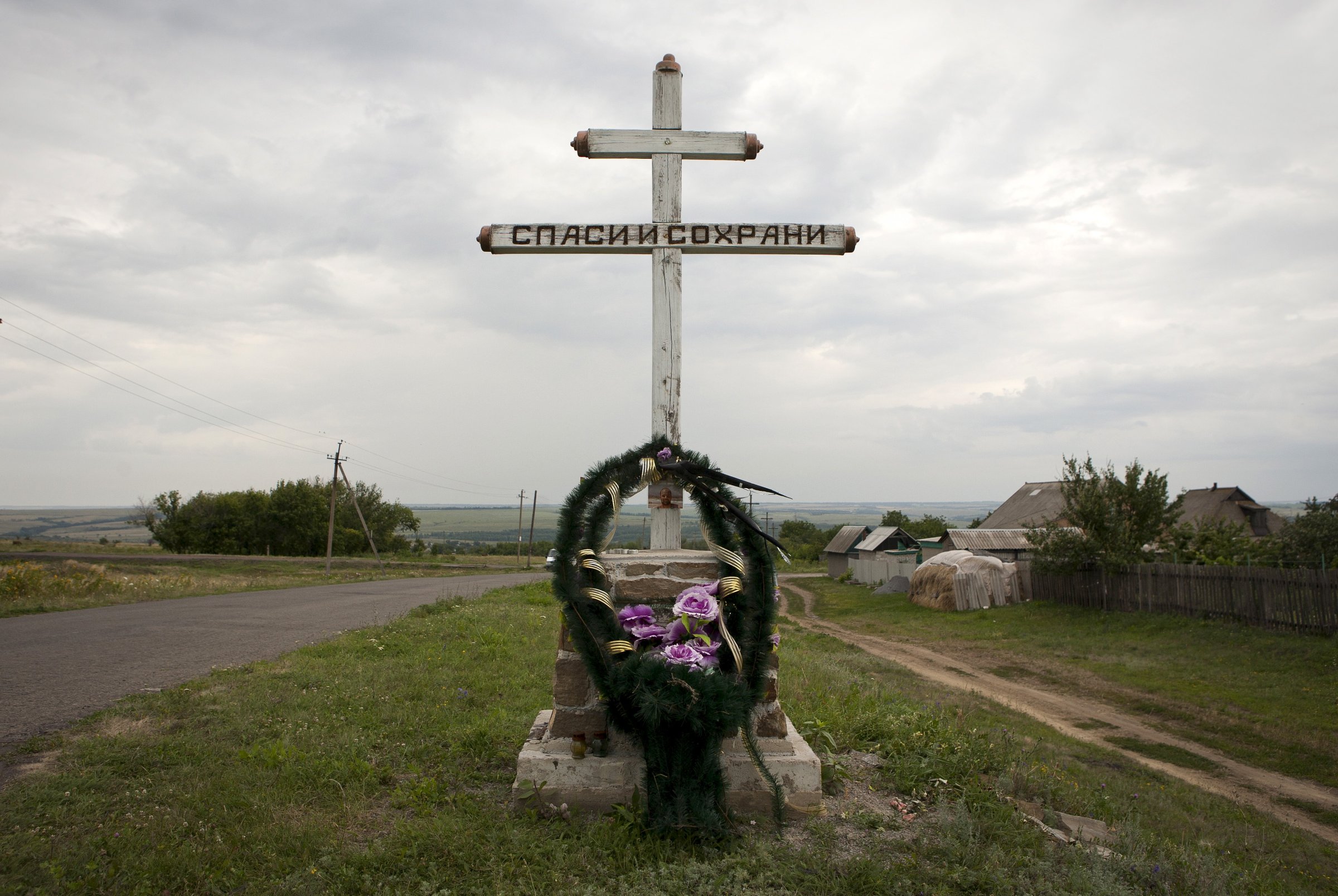 A wreath is placed on a cross with an inscription that reads "Save and protect" next to the site of the downed Malaysia Airlines flight MH17, near the village of Hrabove (Grabovo) in Donetsk region, eastern Ukraine
