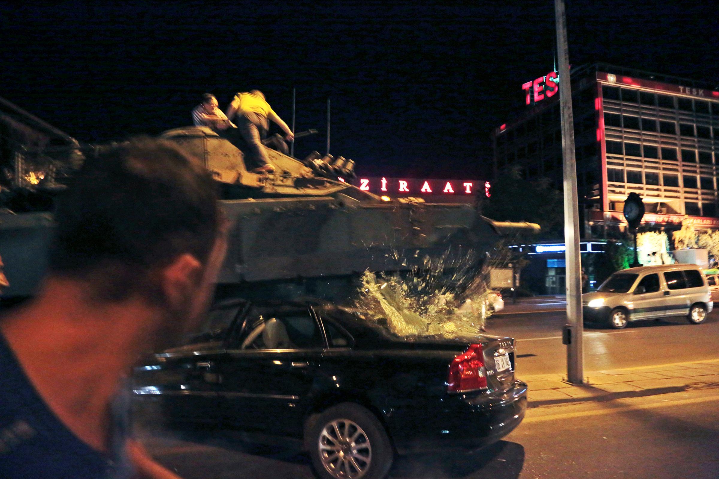 A tank moving into position crashes over a car as people attempt to stop it in Ankara, Turkey, on July 15, 2016.