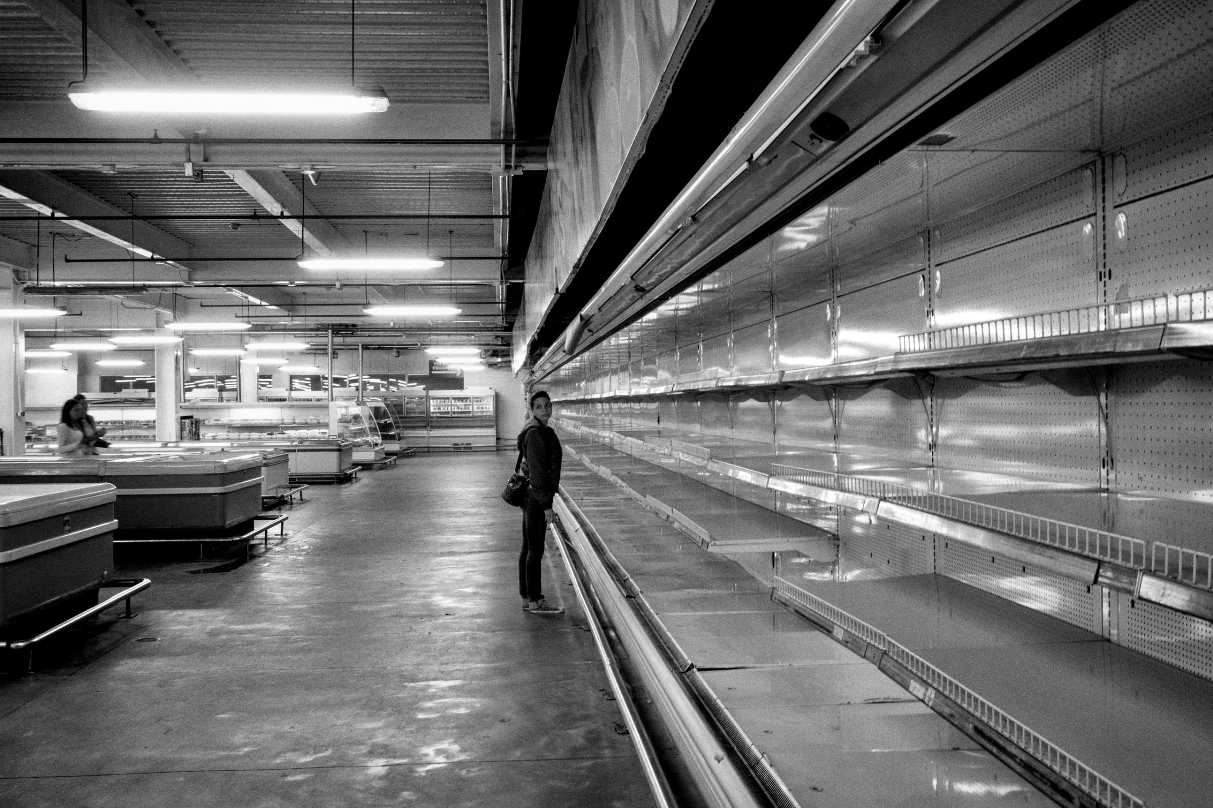A woman stands before empty shelves in one of the major supermarkets in Caracas, Venezuela. The severe political crisis has pushed the country a deep economic decline. Sept. 2015.