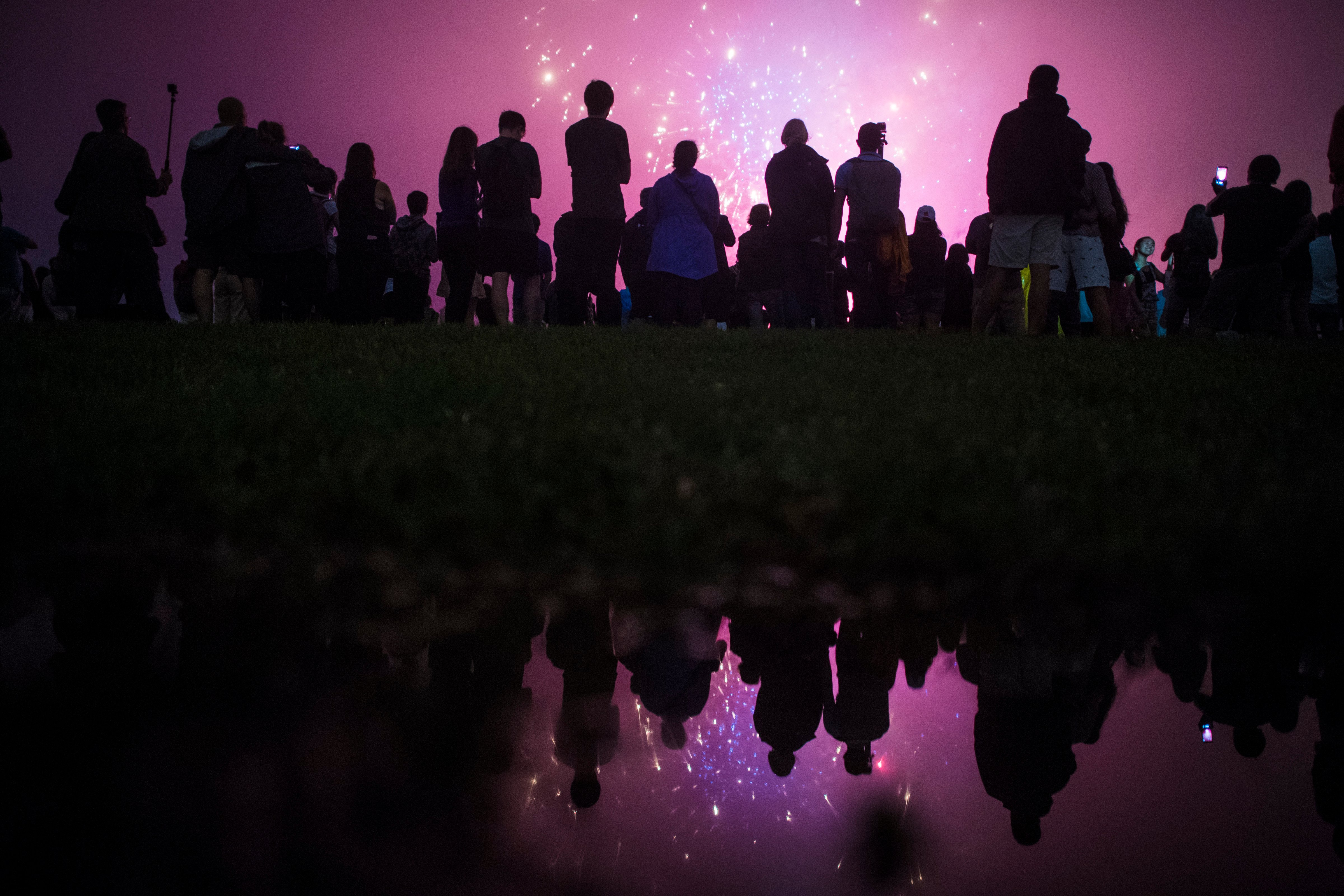 WASHINGTON, DC - JULY 4: Patrons, reflected in a rain puddle, watch near the Washington Monument as the Independence Day fireworks go off on the National Mall in Washington, DC on Monday July 04, 2016. (Photo by Jabin Botsford/The Washington Post via Getty Images) (The Washington Post—Getty Images)