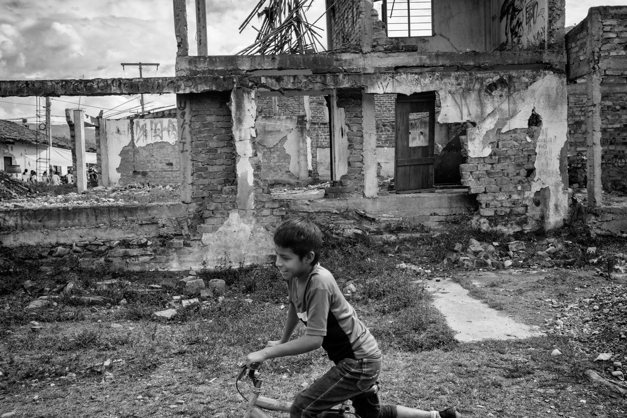 A child rides a bicycle in front of the ruins of a house destroyed in an attack by FARC in the com- munity of Toribio, Colombia. Many regions of Colombia have lived for more than 52 years under FARC's control. A Peace agreement reached in Havana, Cuba on Aug. 24, 2016 raised many doubts and fears among civilians about the future that awaits these communities neglected by the state, Cauca, Colombia, July 2016.
