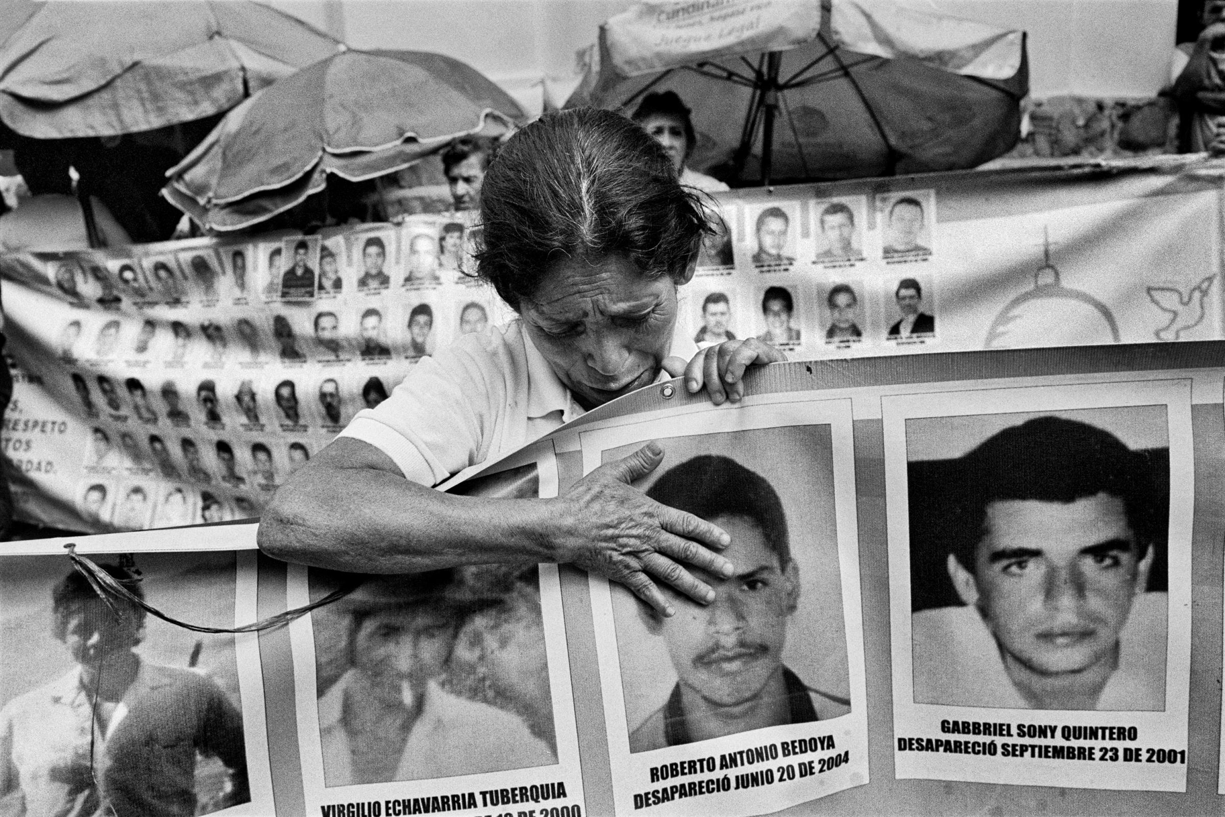 A mother cries to a picture of her missing son during a vigil in the Center of Medellin, Colombia, Feb. 2015. Every Friday, the association of mothers of the candelaria organizes a vigil to remember and demand the return of their missing relatives. There are more than 96,000 people missing in Colombia.