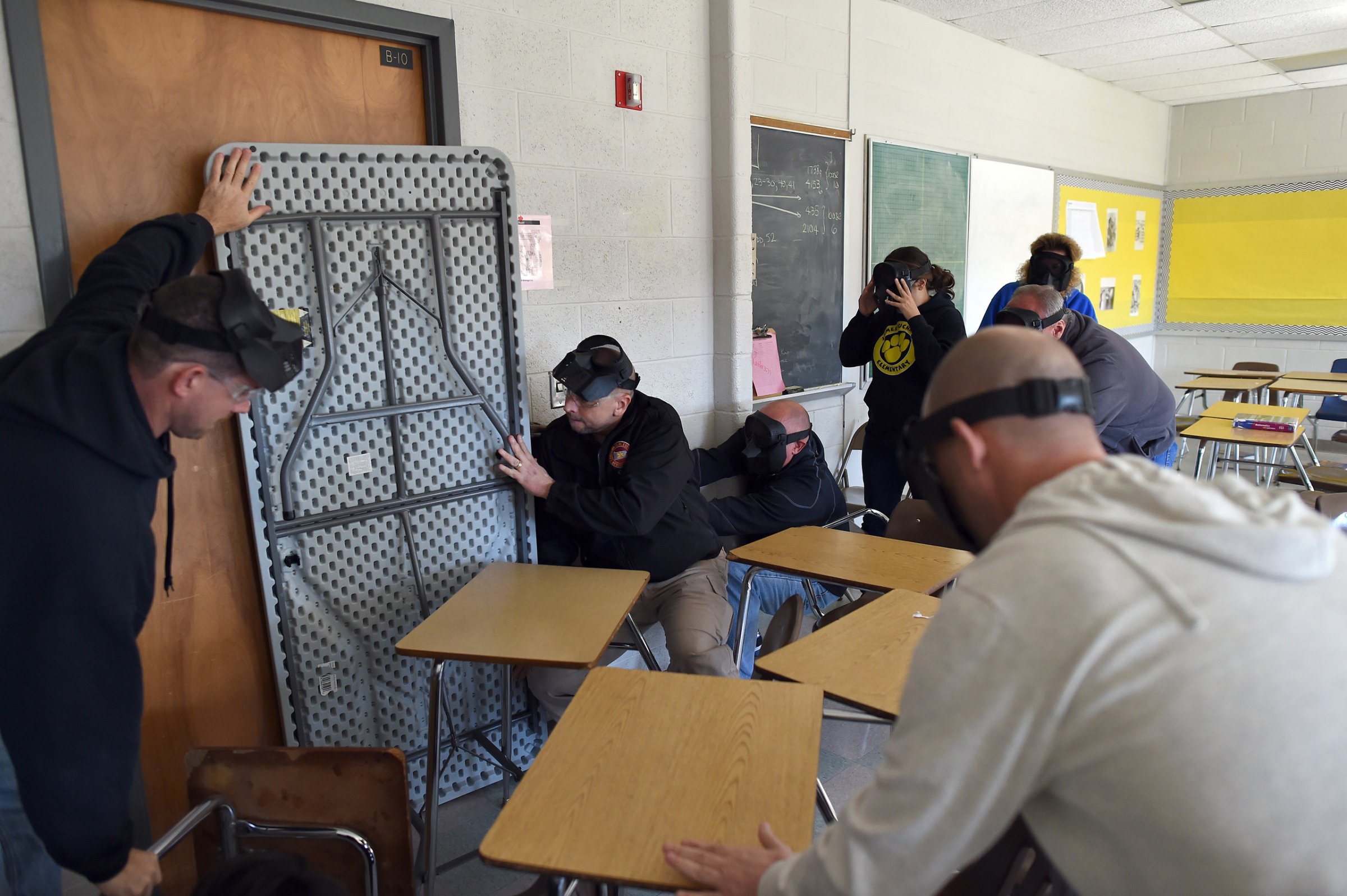 Participants barricade a door of a classroom to block an "active shooter" during ALICE (Alert, Lockdown, Inform, Counter and Evacuate) training at the Harry S. Truman High School in Levittown, Pennsylvania, on November 3, 2015. ALICE is designed to educate local and school-based law enforcement, as well as administrators, teachers and others about the research-based, proactive response approach to violent Intruder events. AFP PHOTO/JEWEL SAMAD (Photo credit should read JEWEL SAMAD/AFP/Getty Images)