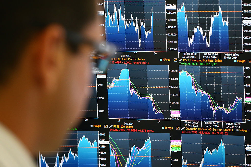 An employee views trading screens at the offices of Panmure Gordon and Co in London on Oct. 20, 2014.