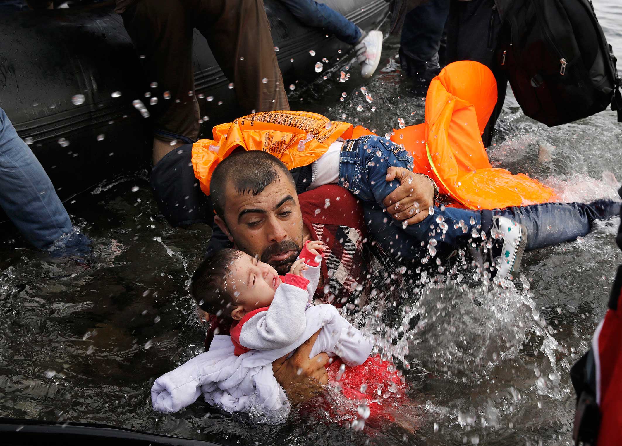A Syrian with his two children struggling to disembark after crossing from Turkey. Island of Lesbos, Sept. 24, 2015.