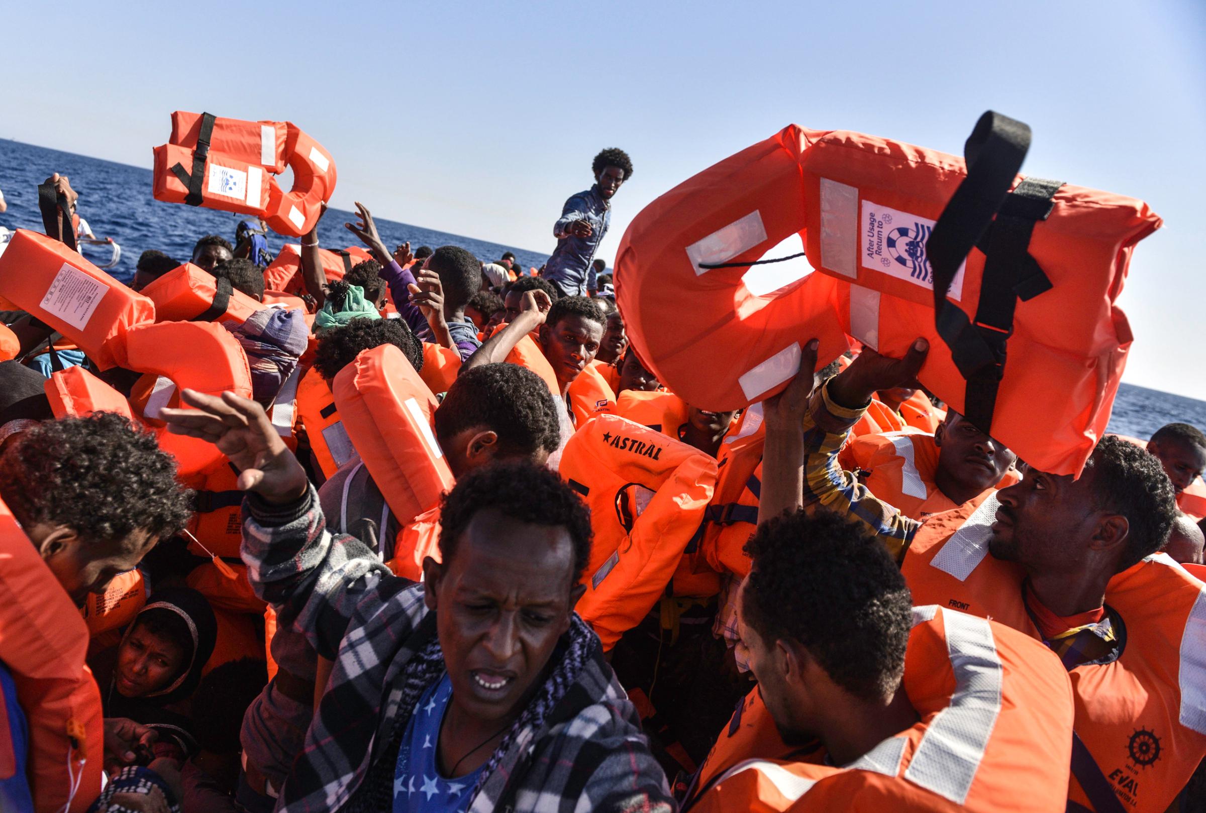 Migrants pass the life jackets being handed out by the search-and-rescue teams with Médecins Sans Frontières and SOS Méditerranée off the coast of Libya, Aug. 21, 2016.