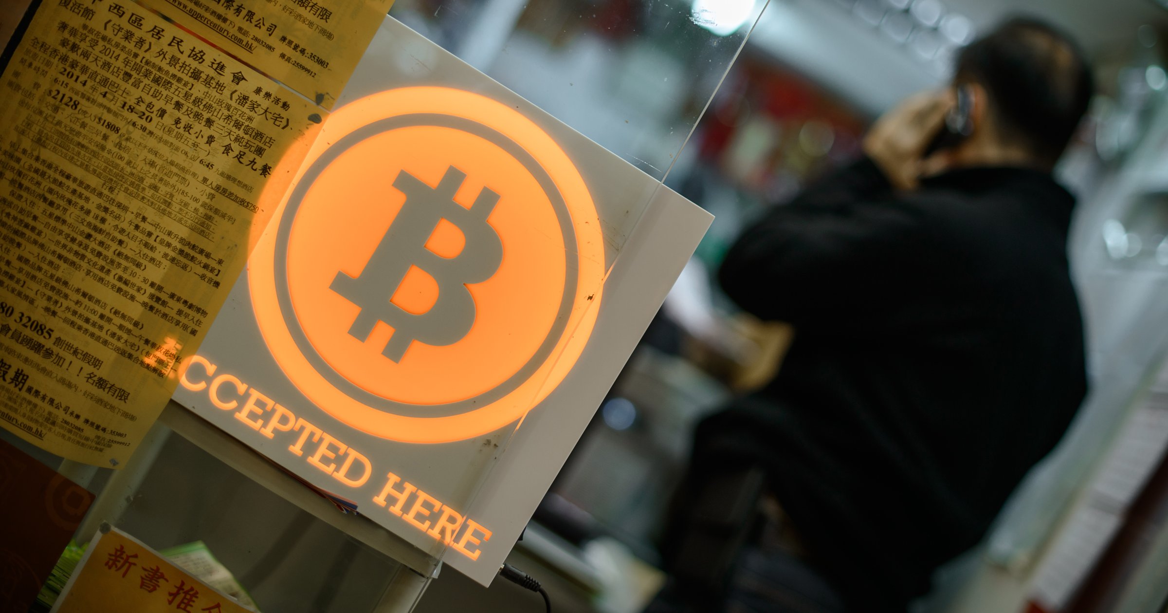 A man talks on a mobile phone in a shop displaying a bitcoin sign during the opening ceremony of the first bitcoin retail shop in Hong Kong on Feb. 28, 2014.