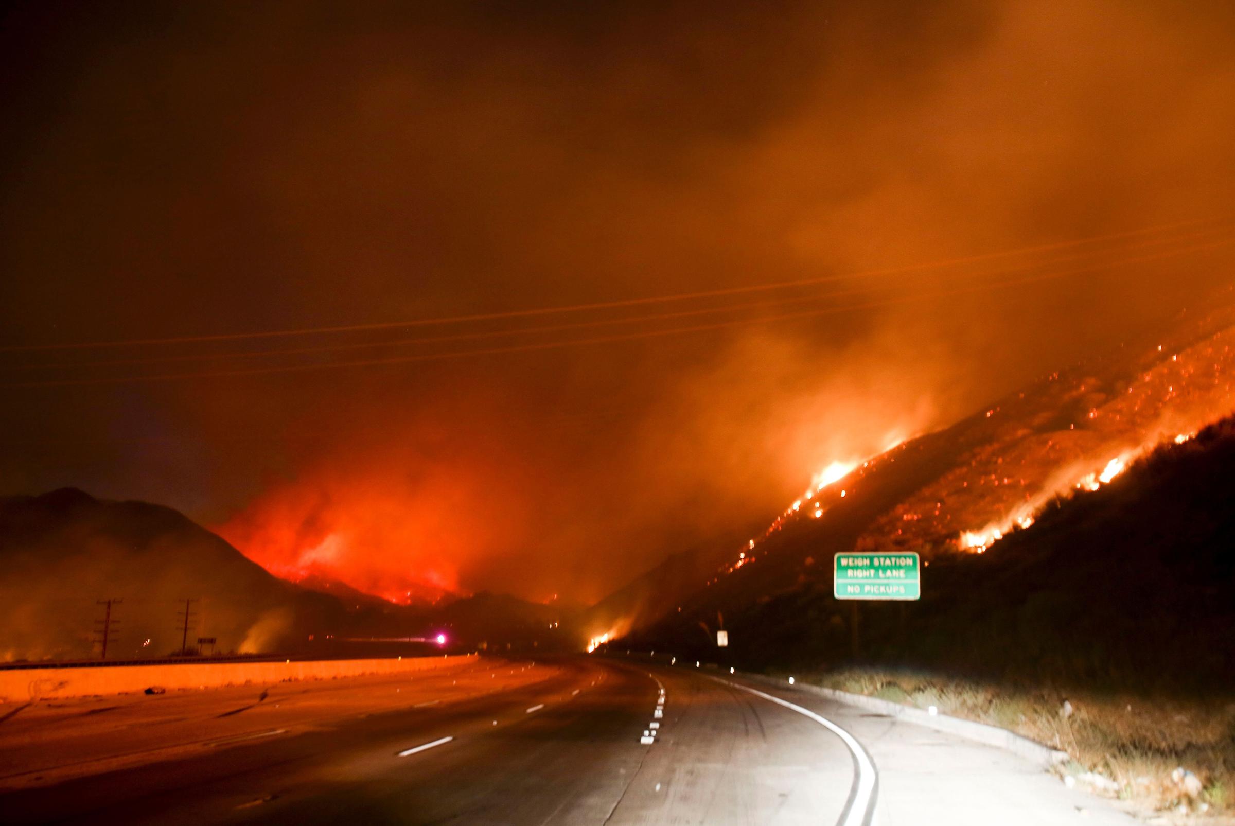 Flames burn next to Interstate 15 as the Blue Cut wildfire rages near Cajon Pass, north of San Bernardino, Calif., Aug. 16, 2016.
