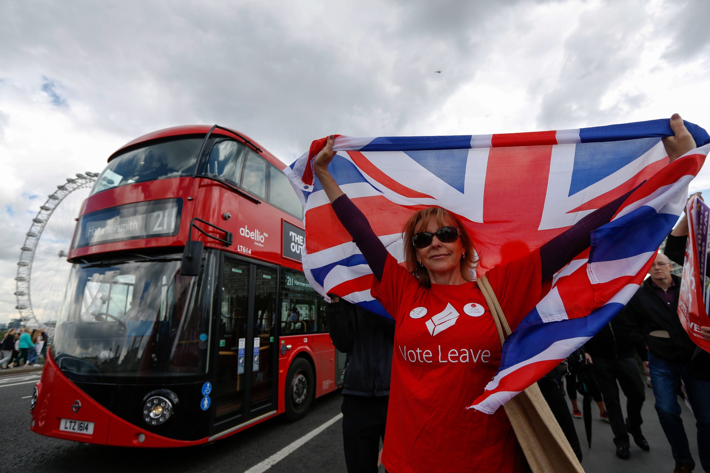 A campaigner wearing a Vote Leave t-shirt and holding a British Union Flag, also known as a Union Jack, stands on a Westminster Bridge near the Houses of Parliament in London on June 15, 2016.