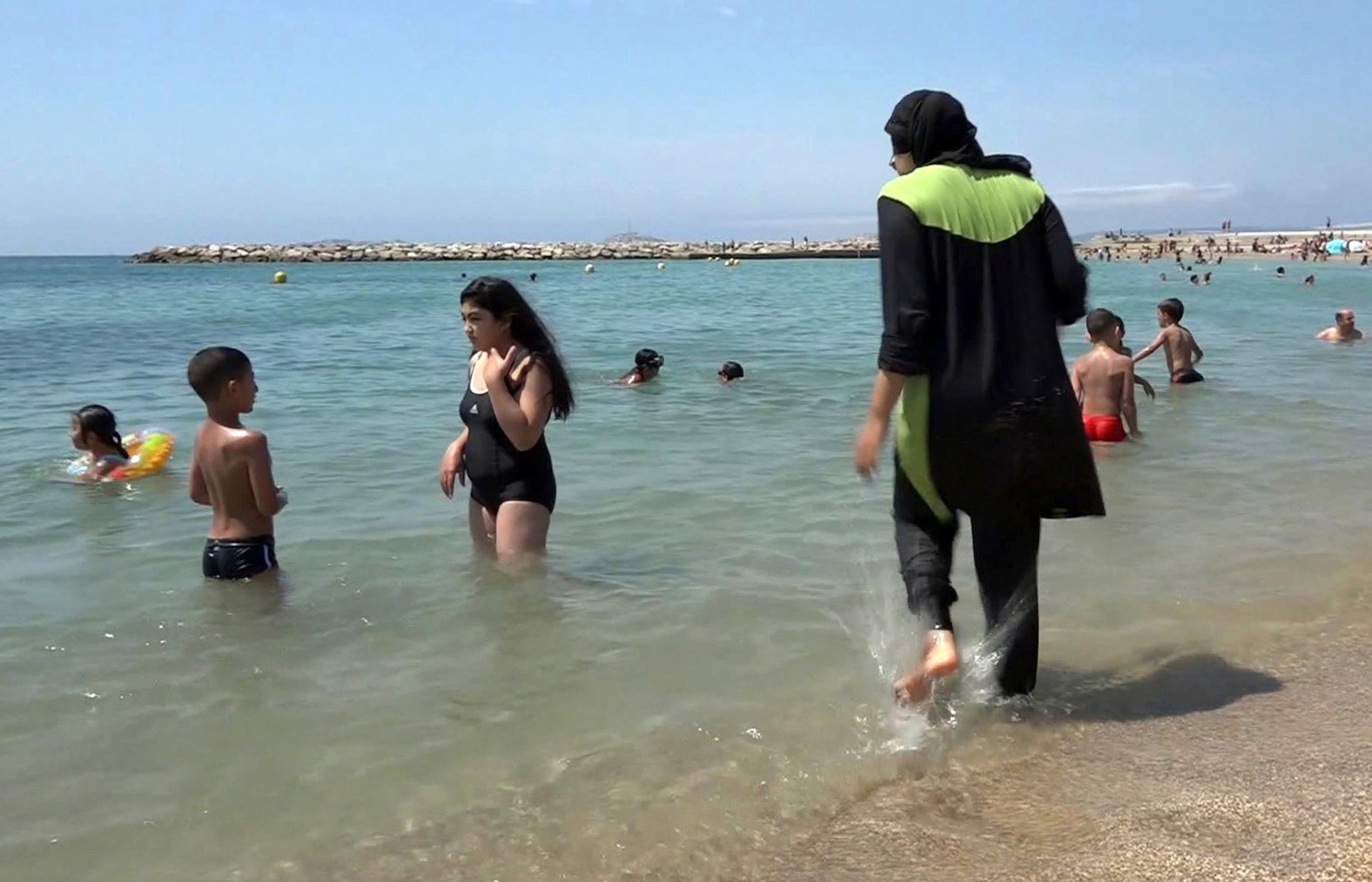 FILE - In this Aug. 4 2016 file photo made from video, Nissrine Samali, 20, gets into the sea wearing a burkini, a wetsuit-like garment that also covers the head, in Marseille, southern France. France's top administrative court has overturned Friday Aug. 26, 2016 a town burkini ban amid shock and anger worldwide after some Muslim women were ordered to remove body-concealing garments on French Riviera beaches. (AP Photo, File)