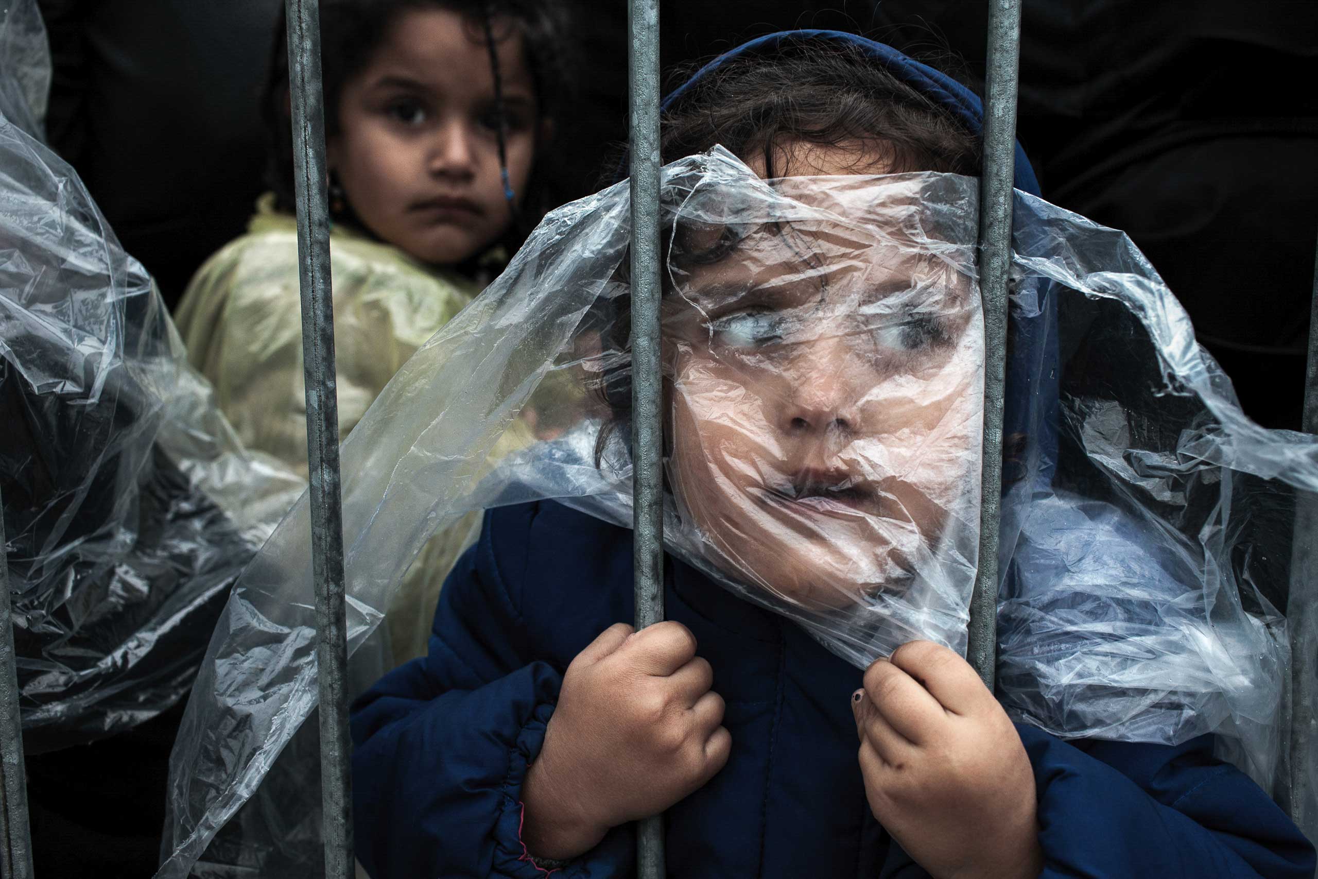 A child is covered with a raincoat while she waits in line to register at a refugee camp in Preševo, Serbia, Oct. 7, 2015. (Matic Zorman)