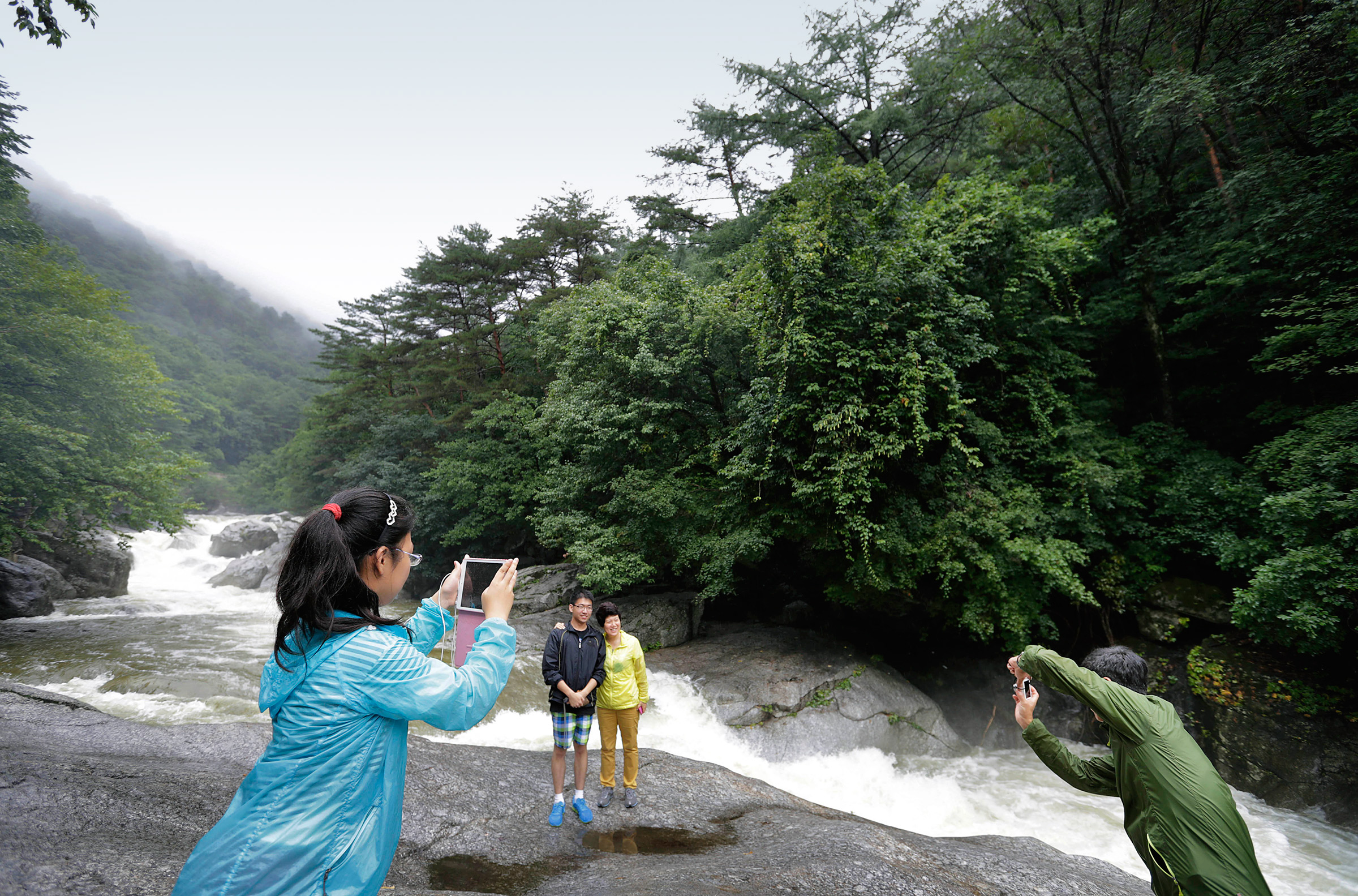 Chinese visitors take photographs at rapids at Mount Myonhyang, a North Korean tourist attraction
