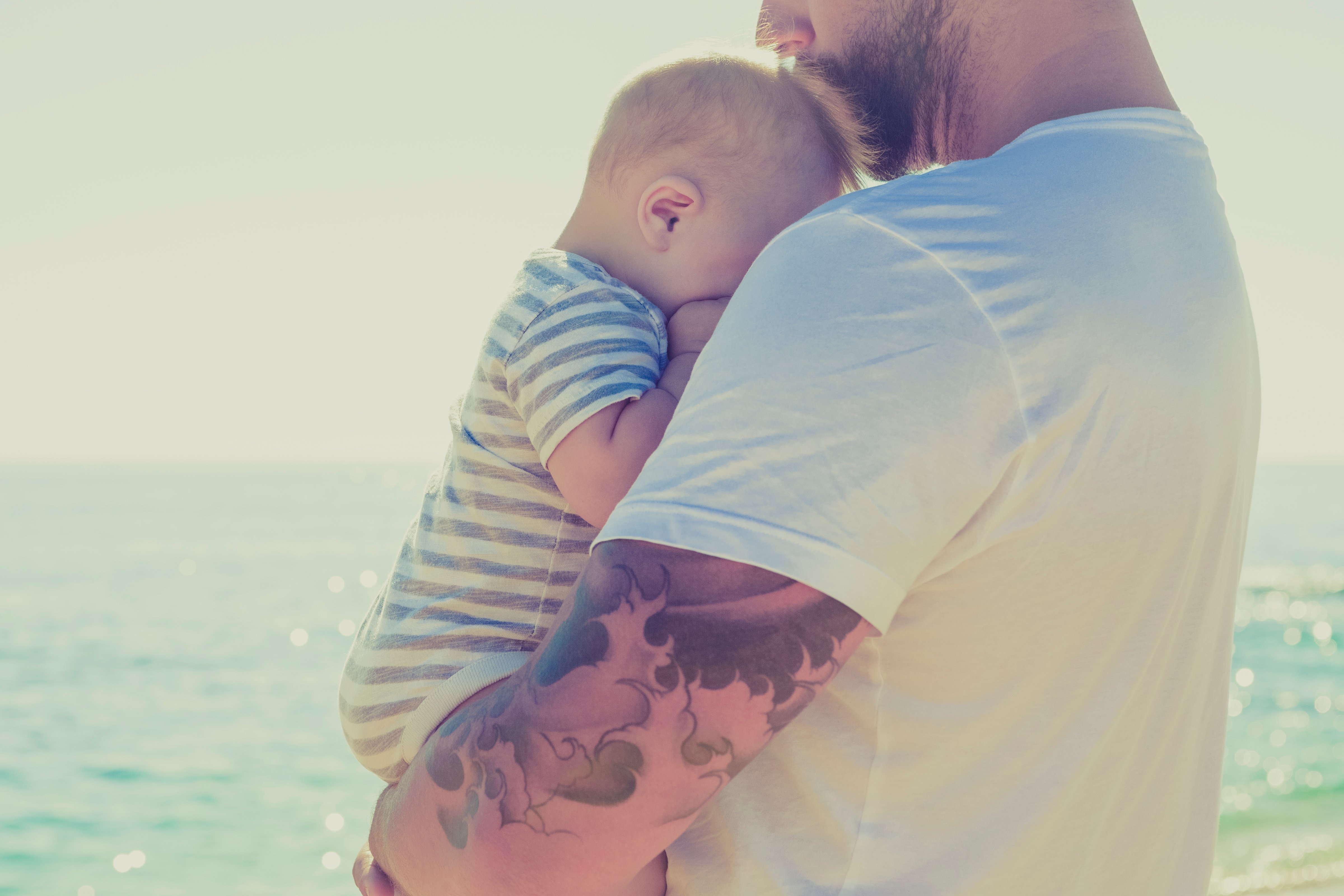 Close up of father holding baby son at beach (Monashee Alonso—Getty Images/Caiaimage)