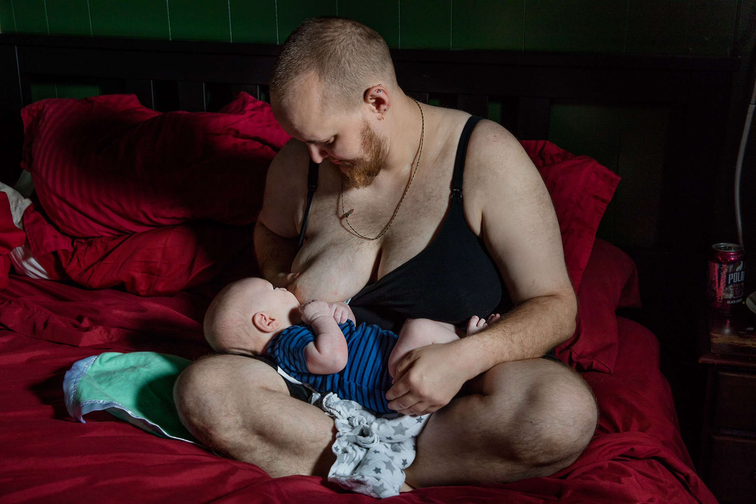 Evan, who stopped his hormone treatments before trying to get pregnant, chest-feeds his newborn son in their Massachusetts home (Elinor Carucci for TIME)