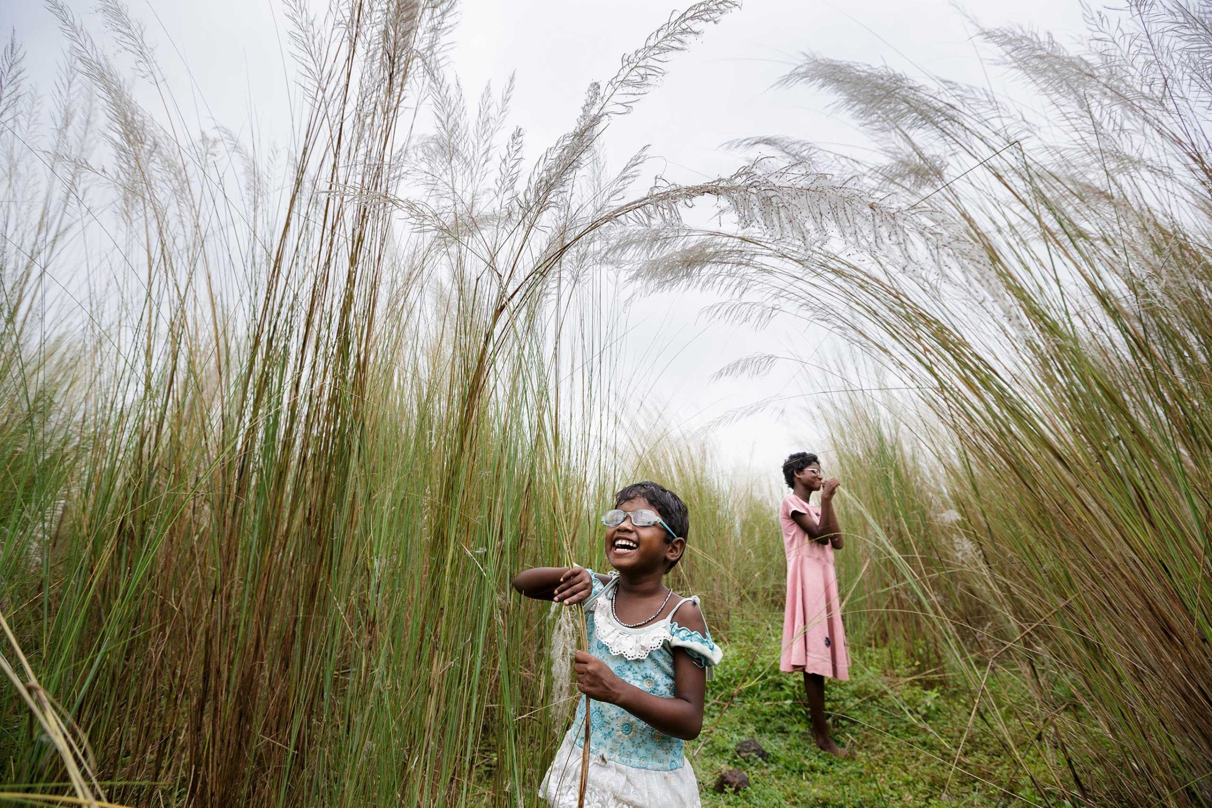 Anita and Sonia explore some of their first sensations of sight after their surgery, as they walk through bulrushes near their village, Oct. 28, 2013 in West Bengal, India.