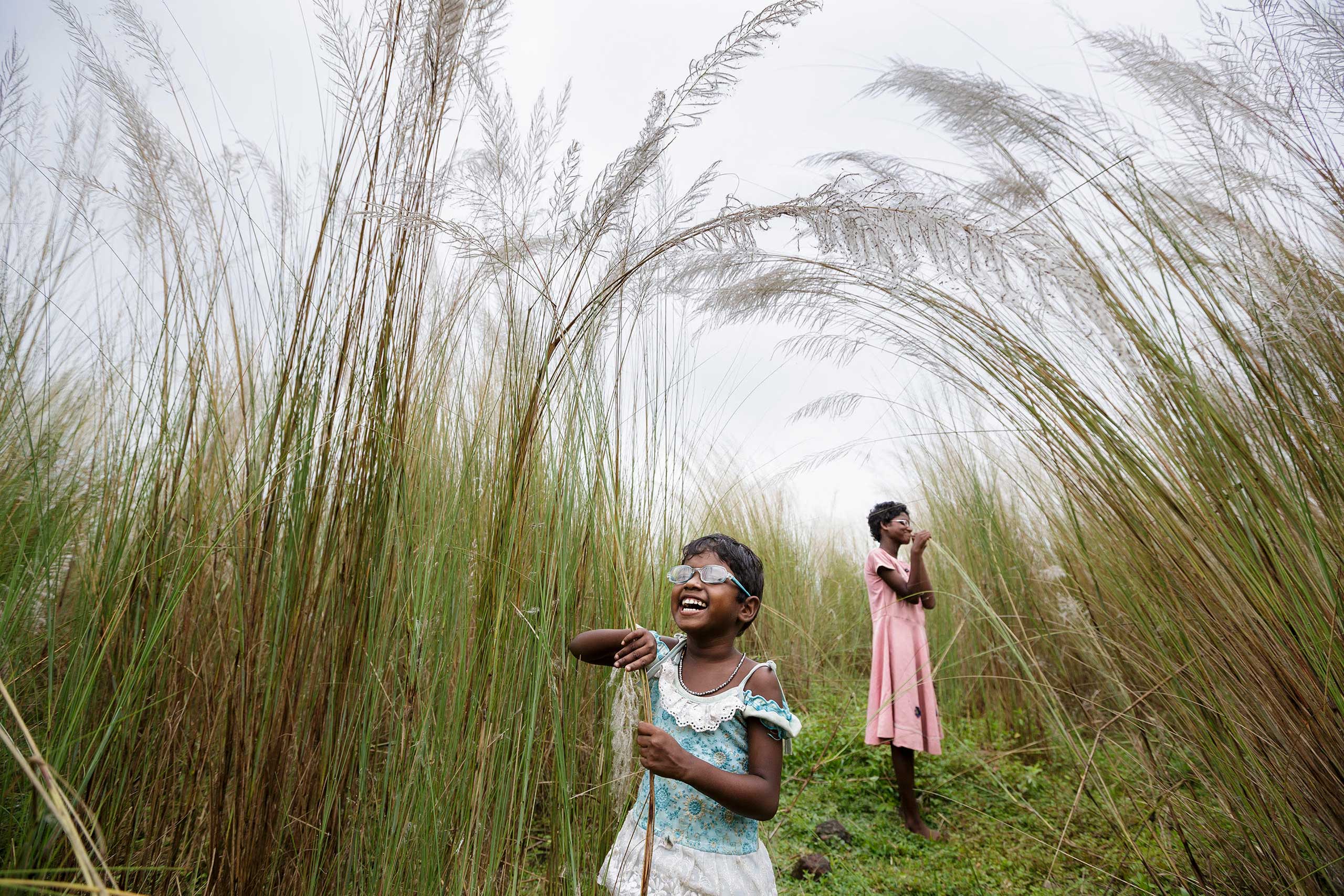 Anita and Sonia explore some of their first sensations of sight after their surgery, as they walk through bulrushes near their village, Oct. 28, 2013 in West Bengal, India. (Brent Stirton—Getty Images Reportage)