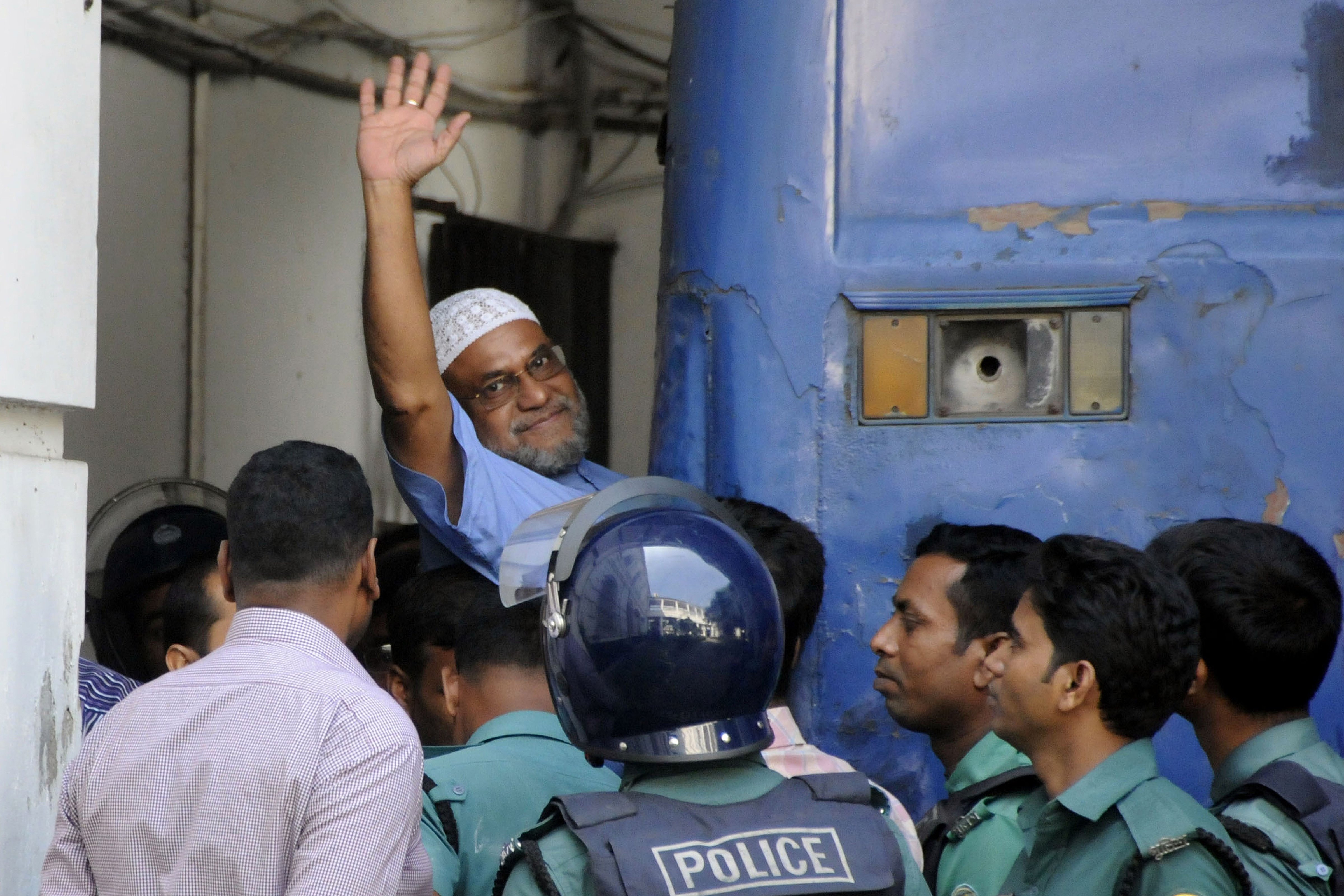 Bangladeshi Jamaat-e-Islami party leader, Mir Quasem Ali, waves his hand as he enters a van at the International Crimes Tribunal court in Dhaka on Nov. 2, 2014 (Stringer—AFP/Getty Images)