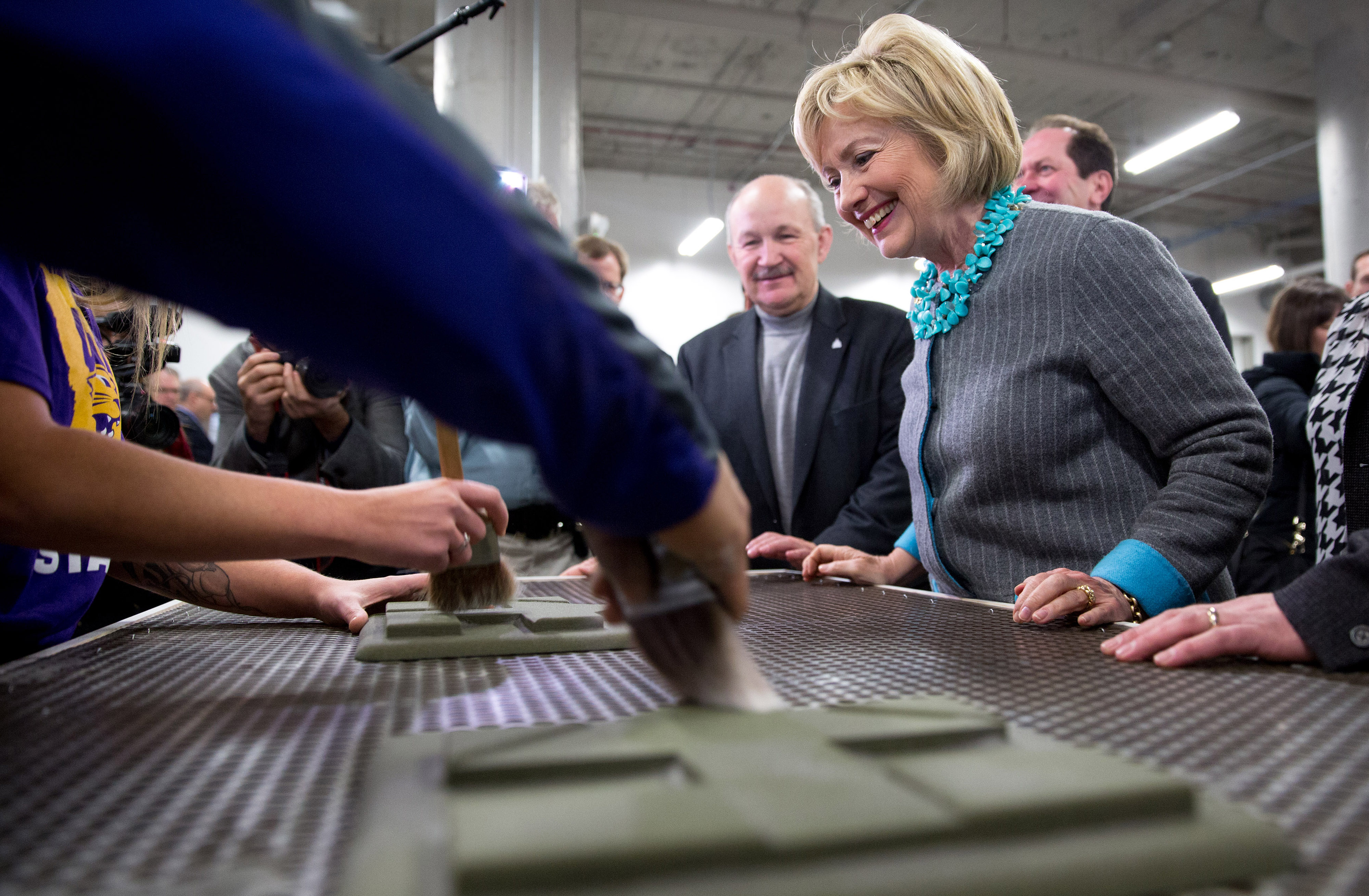 Hillary Clinton, former Secretary of State and 2016 Democratic presidential candidate, watches as students clean off 3D printed campaign logos made for her during a tour of the University of Northern Iowa's Additive Manufacturing Center at Cedar Valley TechWorks in Waterloo, Iowa, U.S., on Wednesday, Dec. 9, 2015. (Bloomberg&mdash;Bloomberg via Getty Images)