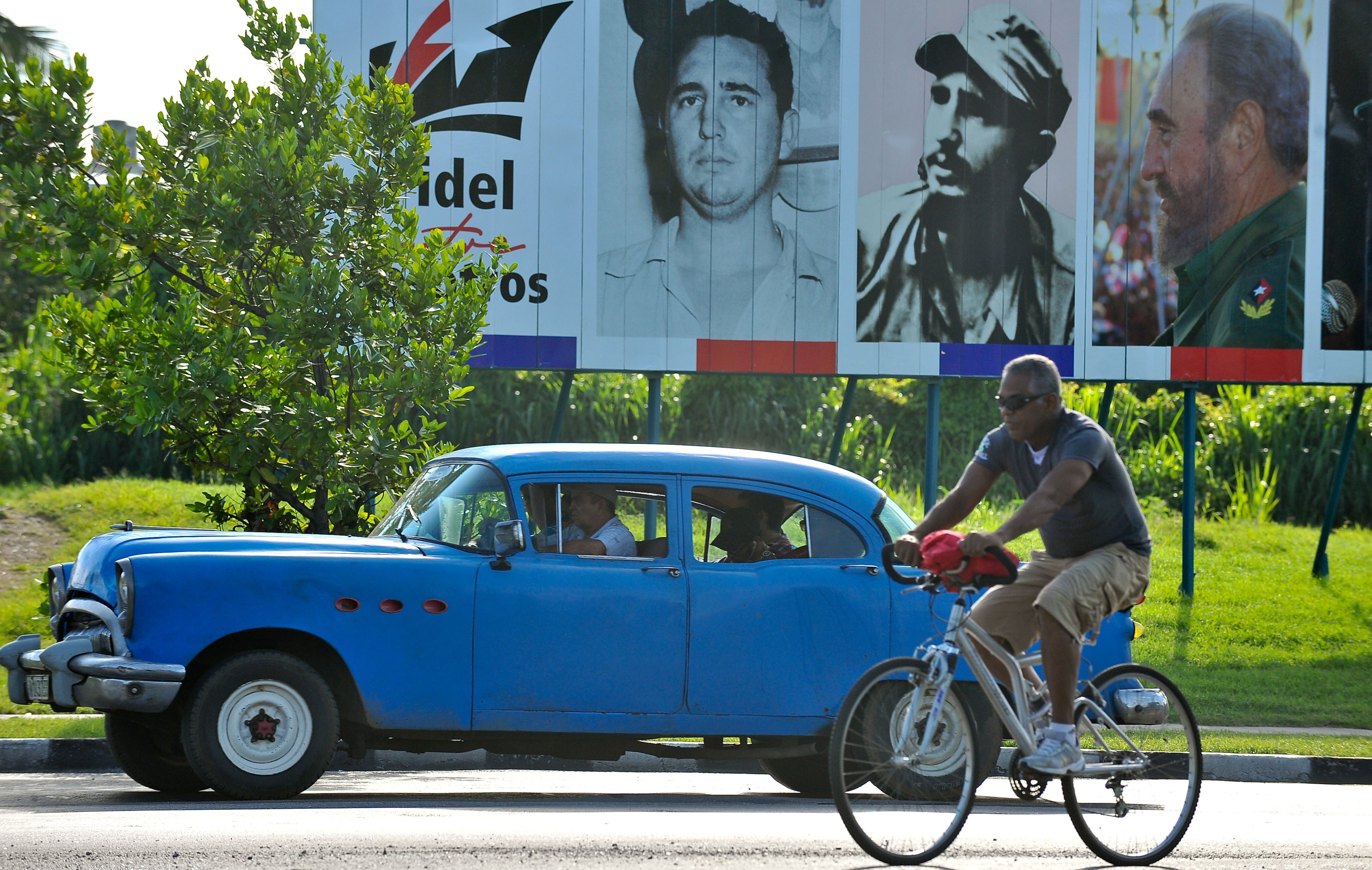 An old American car drives past a billboard of Cuban former President Fidel Castro in Havana on August 12, 2016. (Yamil Lage—AFP/Getty Images)