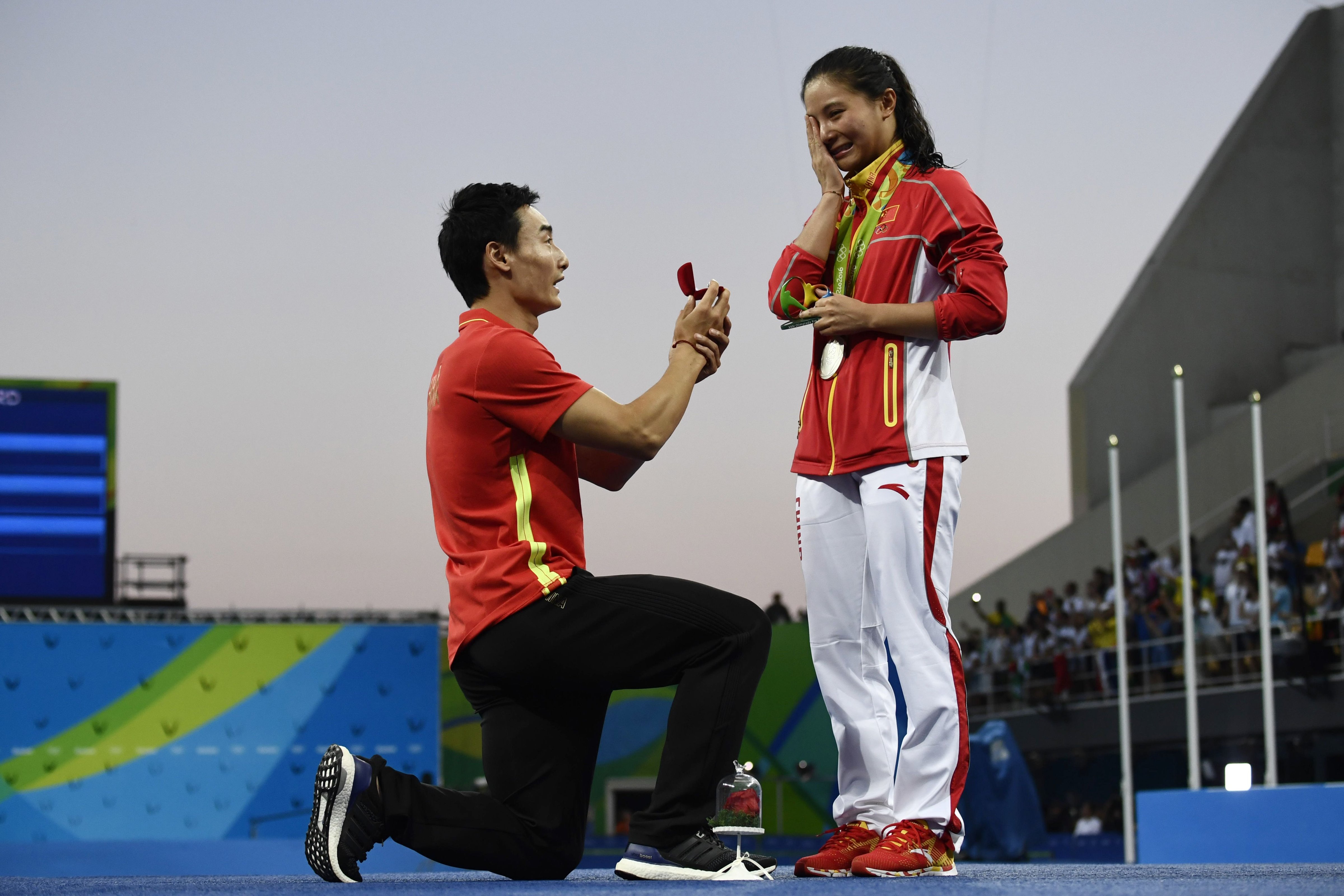 China's silver medalist He Zi, right, receives a marriage proposal from bronze medalist and fellow Chinese diver Qin Kai during the podium ceremony of the women's diving 3-m springboard final in Rio de Jainero on Aug. 14, 2016 (Christophe Simon—AFP/Getty Images)