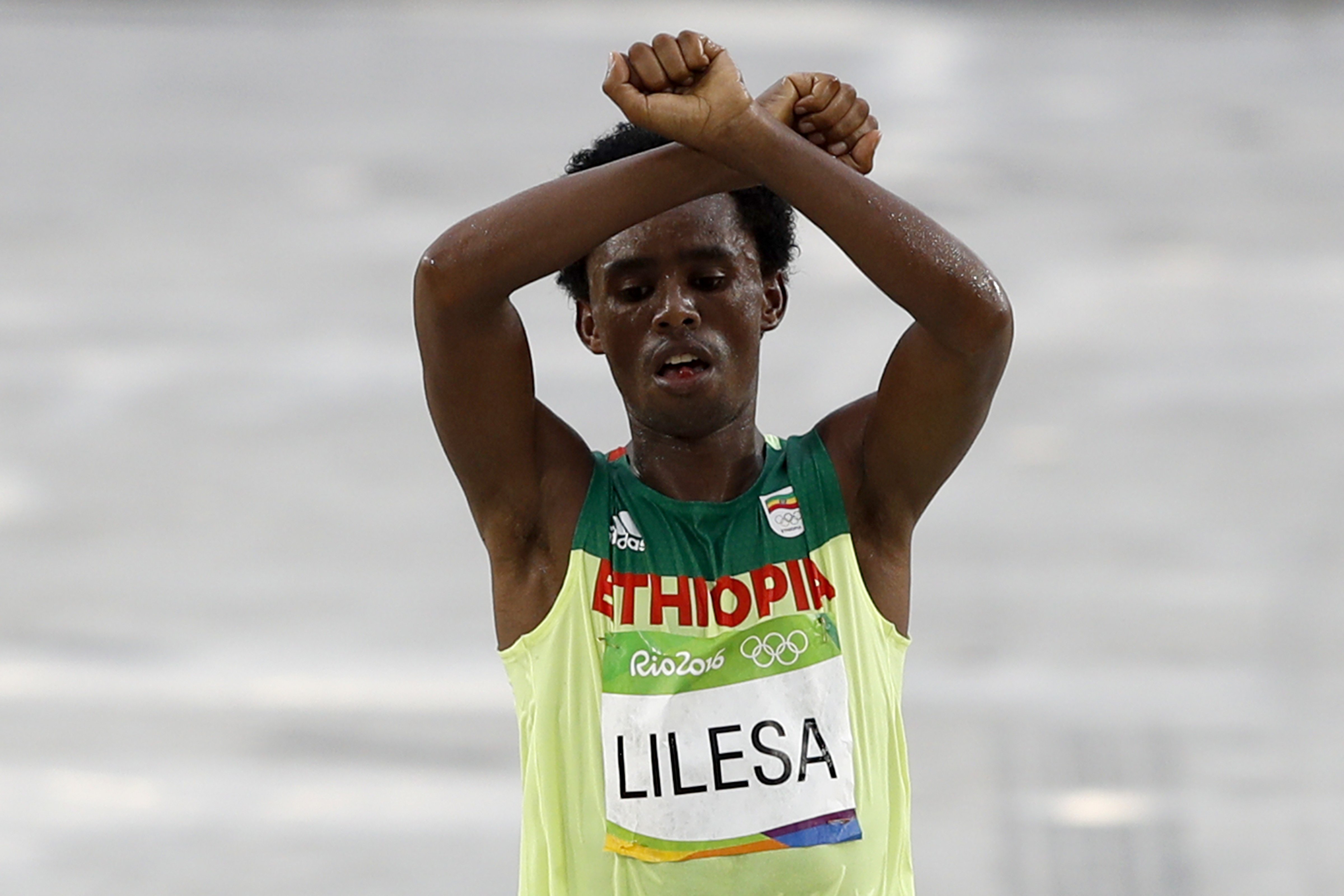 Ethiopia's Feyisa Lilesa (silver) crosses the finish line of the Men's Marathon athletics event during the Rio 2016 Olympic Games at the Sambodromo in Rio de Janeiro on August 21, 2016.  
                      Lilesa crossed his arms above his head as he finished the race as a protest against the Ethiopian government's crackdown on political dissent. (Adrian Dennis—AFP/Getty Images)