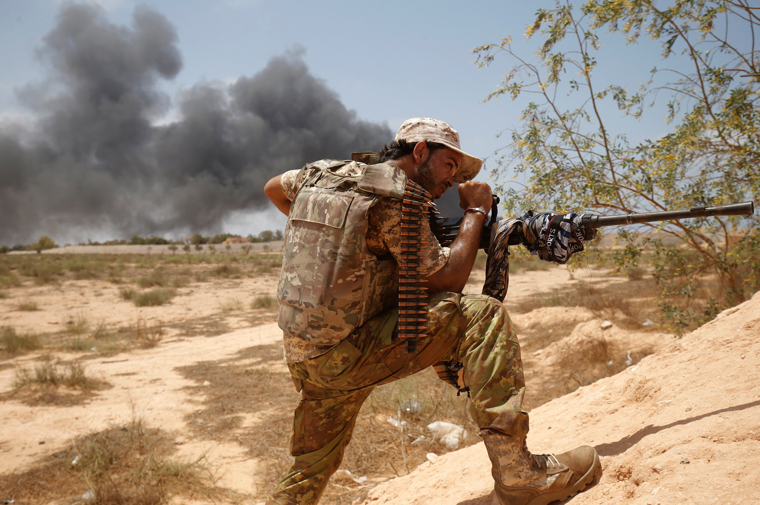A member of the Libyan forces allied with the U.N.-backed unity government fires his gun at ISIS fighters during a battle in Sirt, Libya, on July 15, 2016.