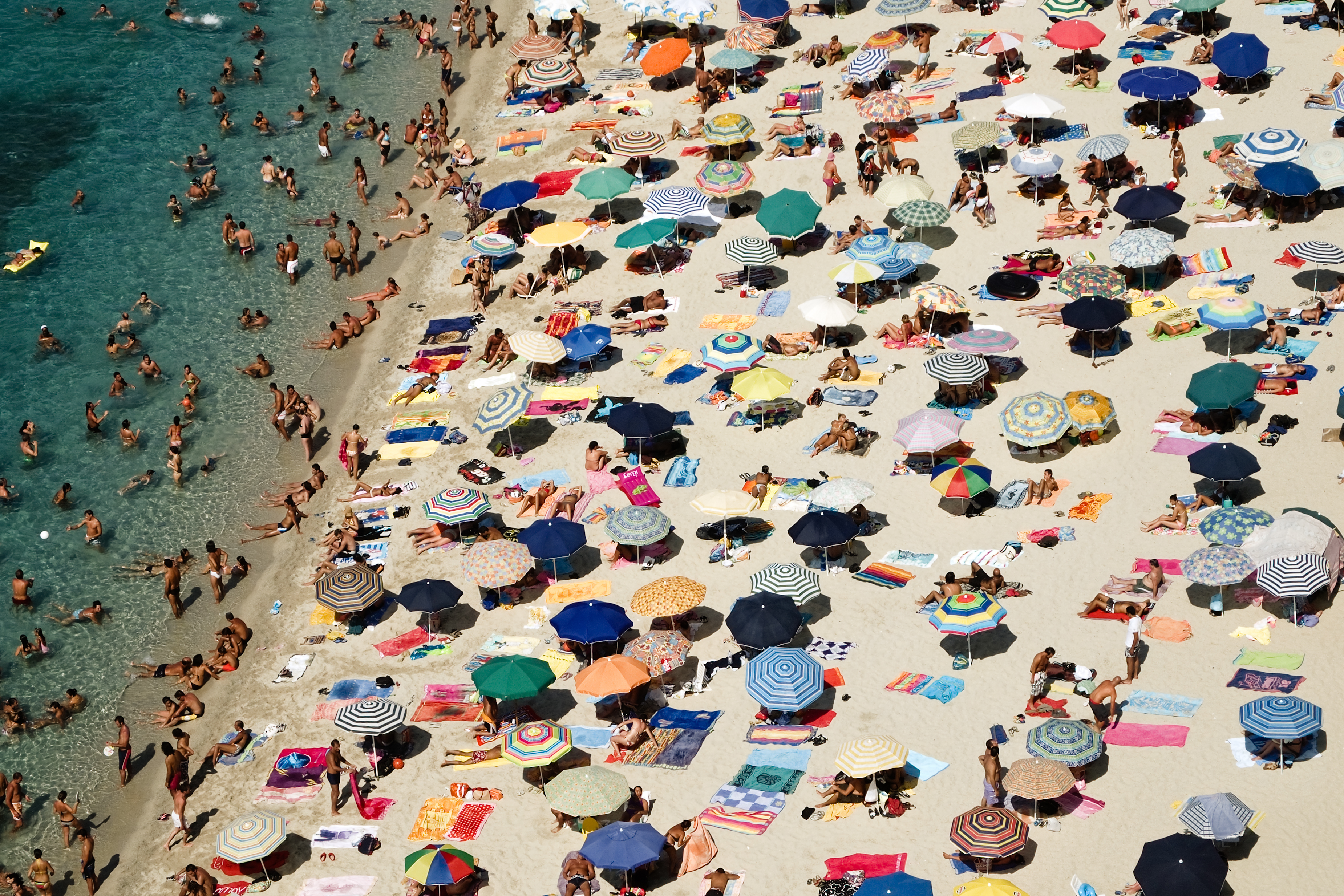 Peoples with umbrella enjoying on beach, Italy. (Marco Casse—Getty Images)
