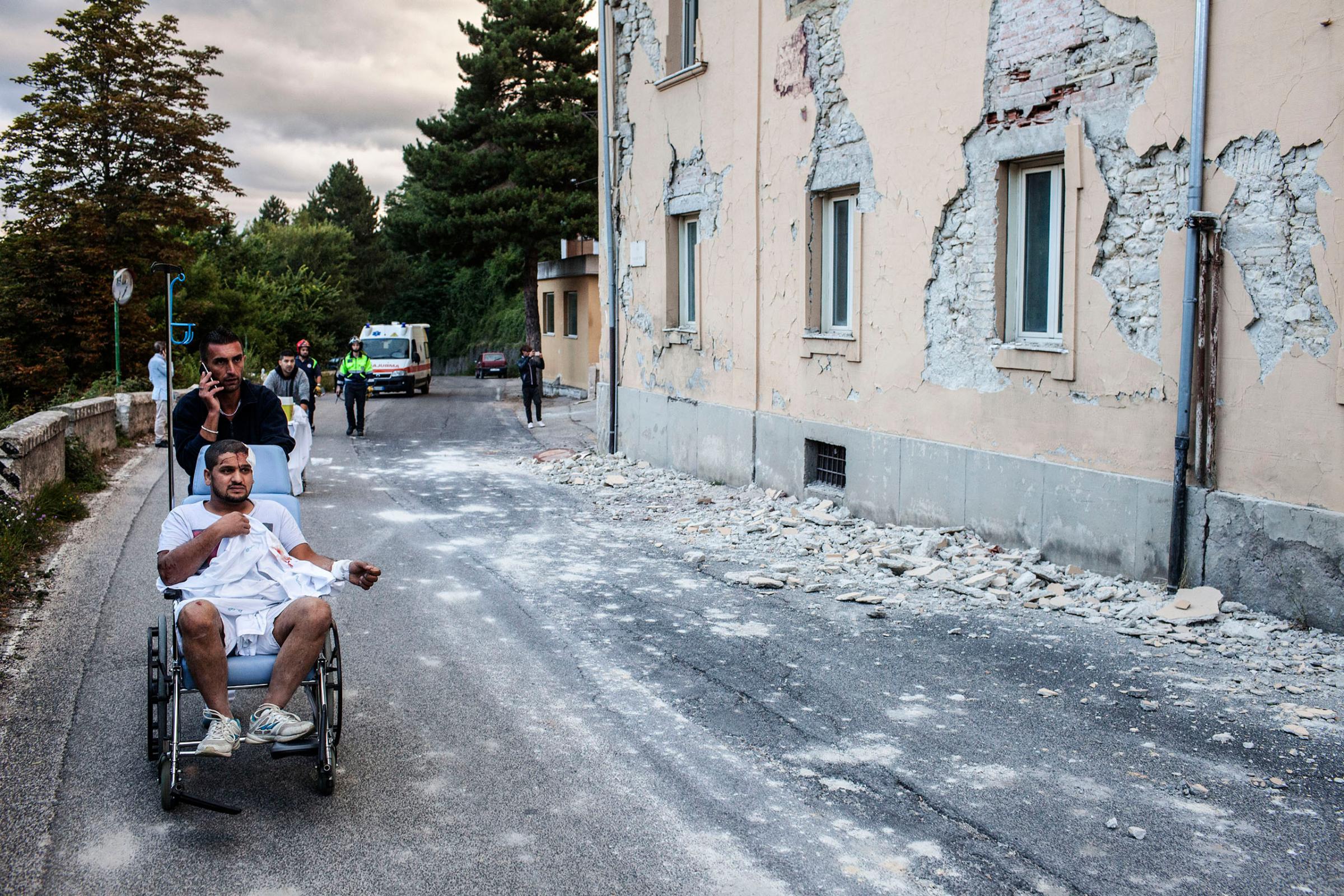 An injured man on a wheelchair outside the hospital in Amatrice, Italy, on Aug. 24, 2016.