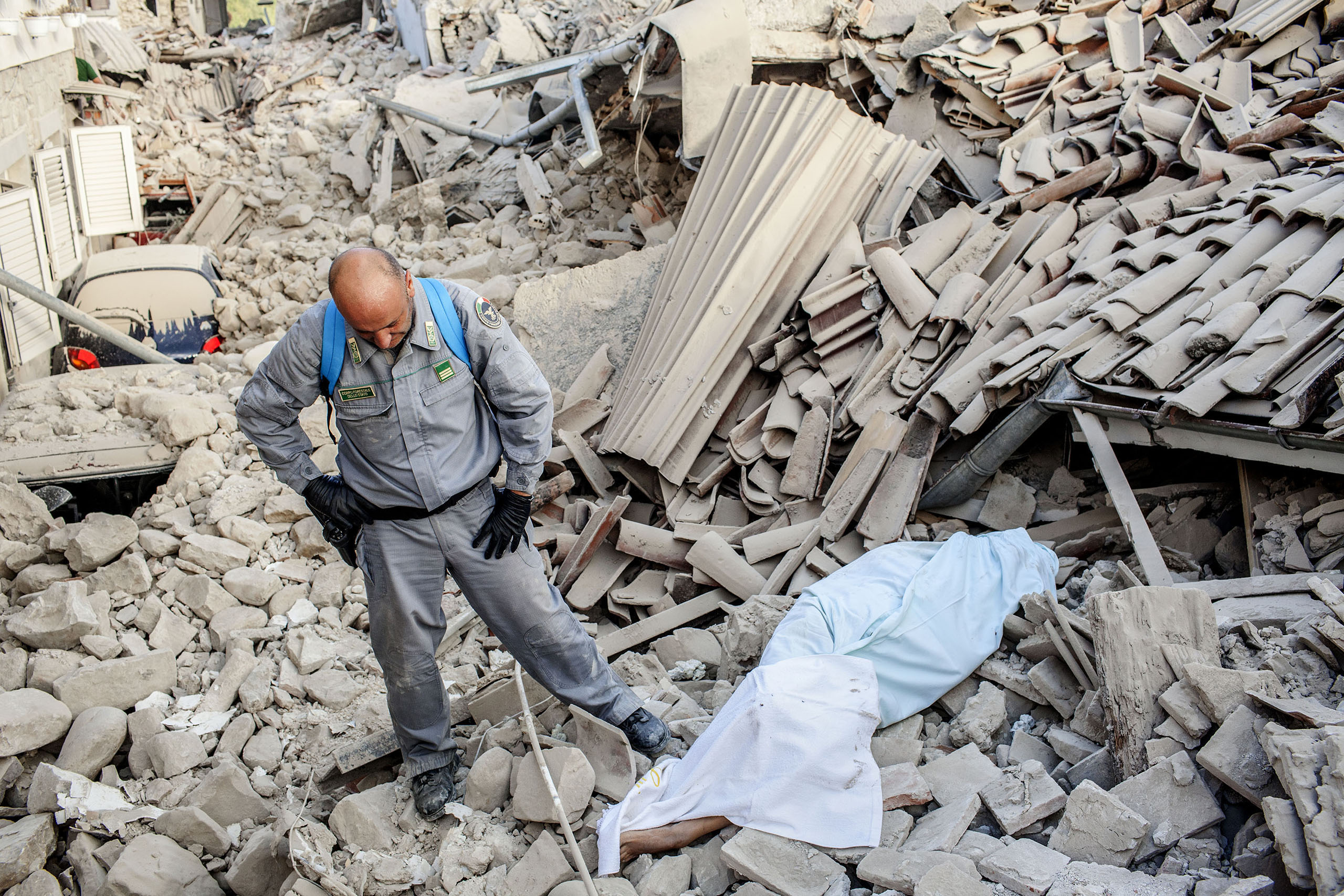 A rescuer stands beside the body of a man pulled from the rubble in the town of Amatrice, Italy, on Aug. 24, 2016.