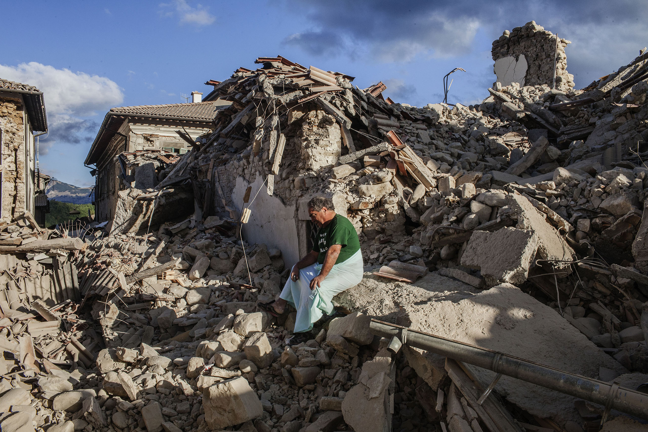 A man sits on the rubble in front of his house that was completely destroyed by the earthquake in Amatrice, Italy, on Aug. 24, 2016.