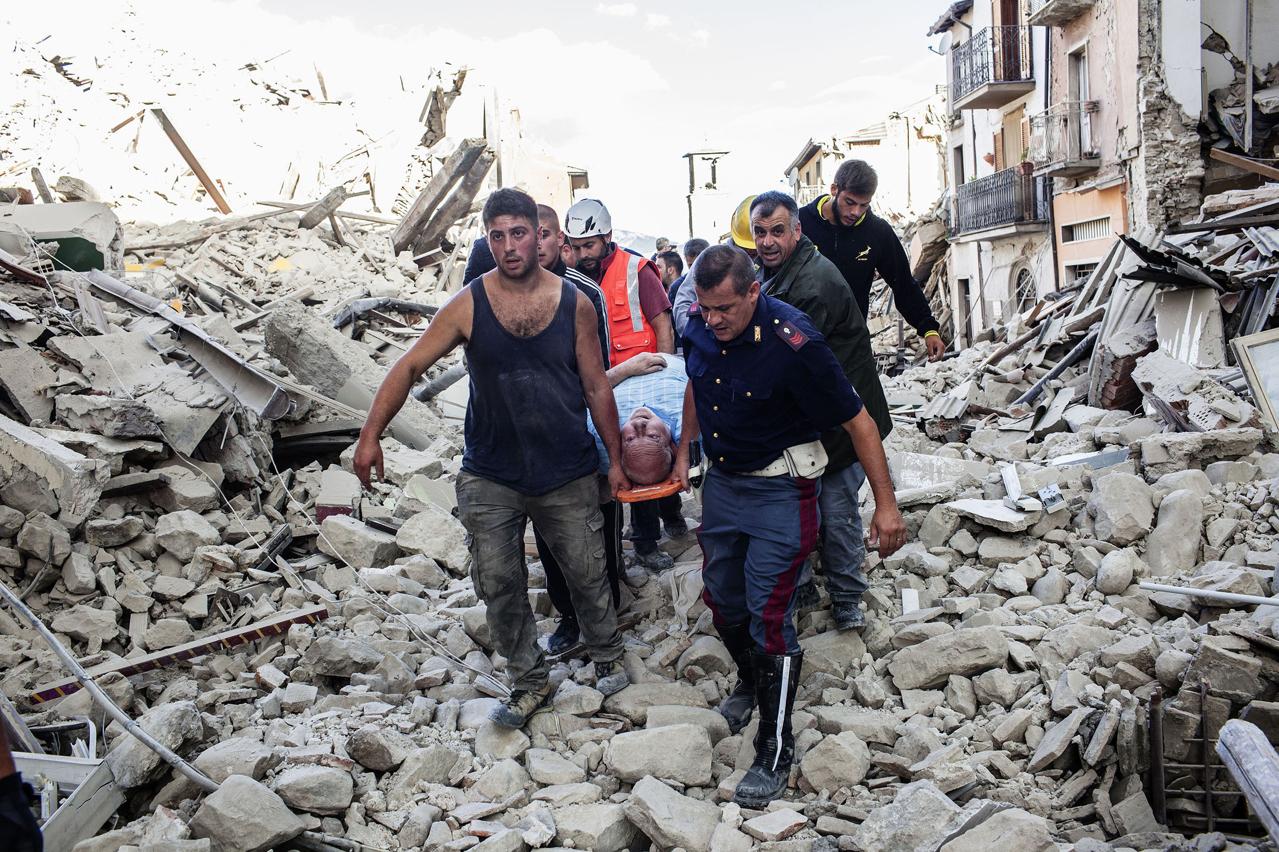 Rescue teams carry a man across the rubble of Amatrice, Italy, on Aug. 24, 2016.