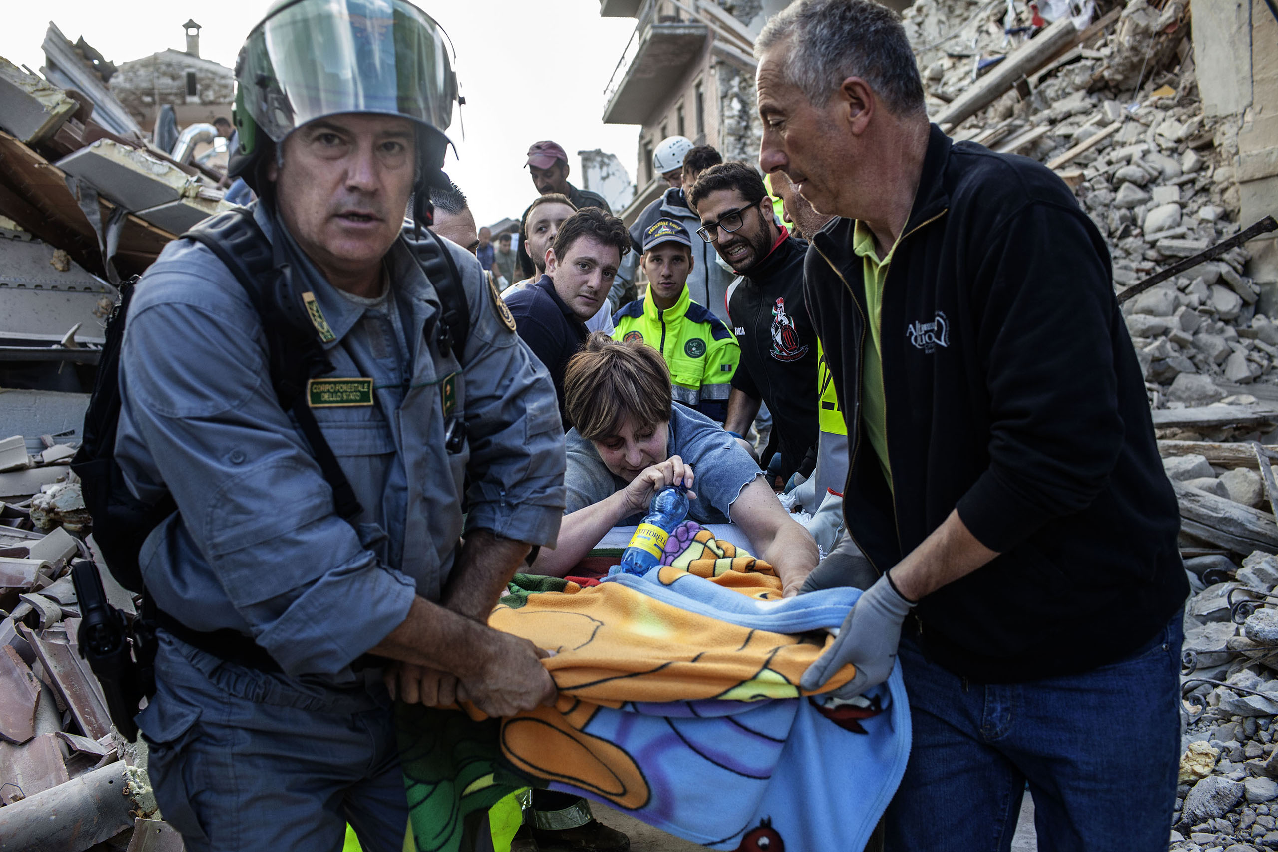 Rescue teams carry a woman to safety in Amatrice, Italy, on Aug. 24, 2016.