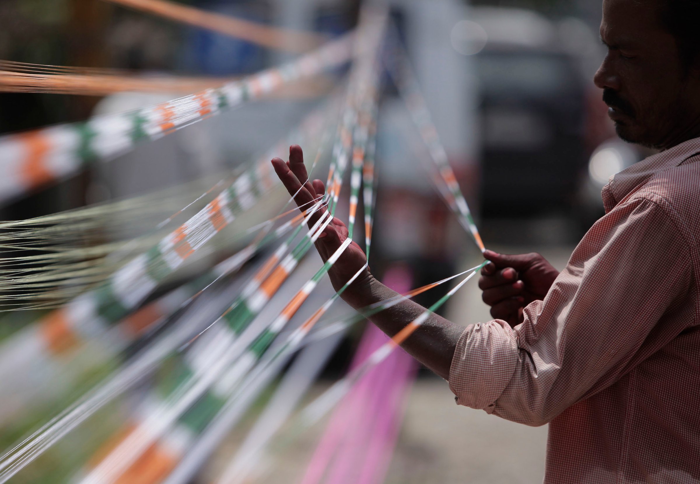 A professional thread maker prepares threads with the three colors of the Indian flag for flying kites in Jammu, India, Aug.13, 2016.