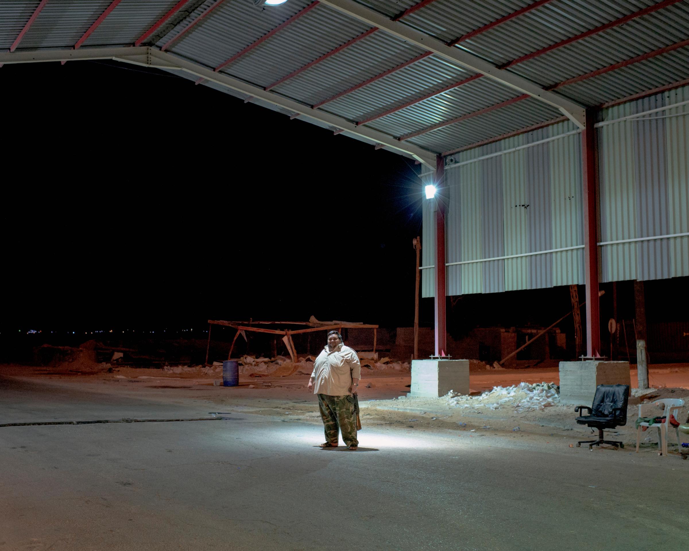 A Libyan fighter guards the Abu Grain checkpoint at night, July 2016.