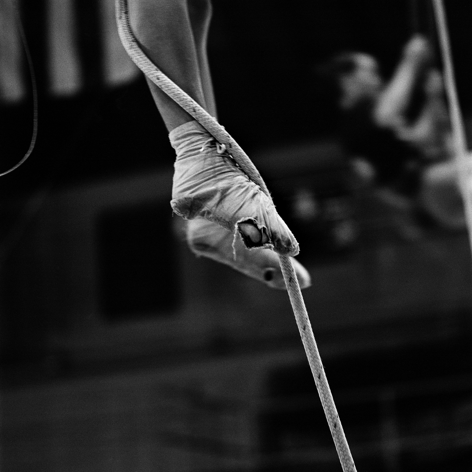 A performer climbs a rope to reach the single trapeze, wearing last year's custom-made performance slippers. Performers are required to buy their own slippers, but they are re-used for practice. Circus personnel viewed this image as a testament to how hard all the young kids practice, how dedicated they are, and how frugal.
