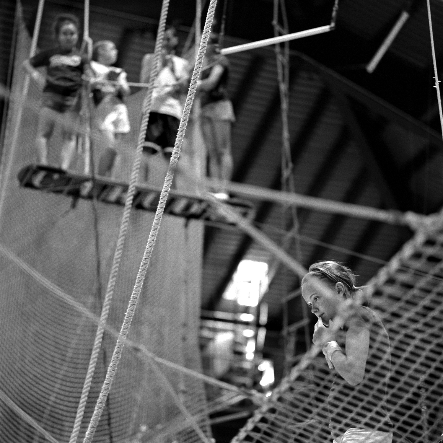 Josie Murphy, 13, ponders advice from her trainer on the flying trapeze while others await their turn to practice. For the most challenging acts, performers are selected earl, based on their potential and suitability.