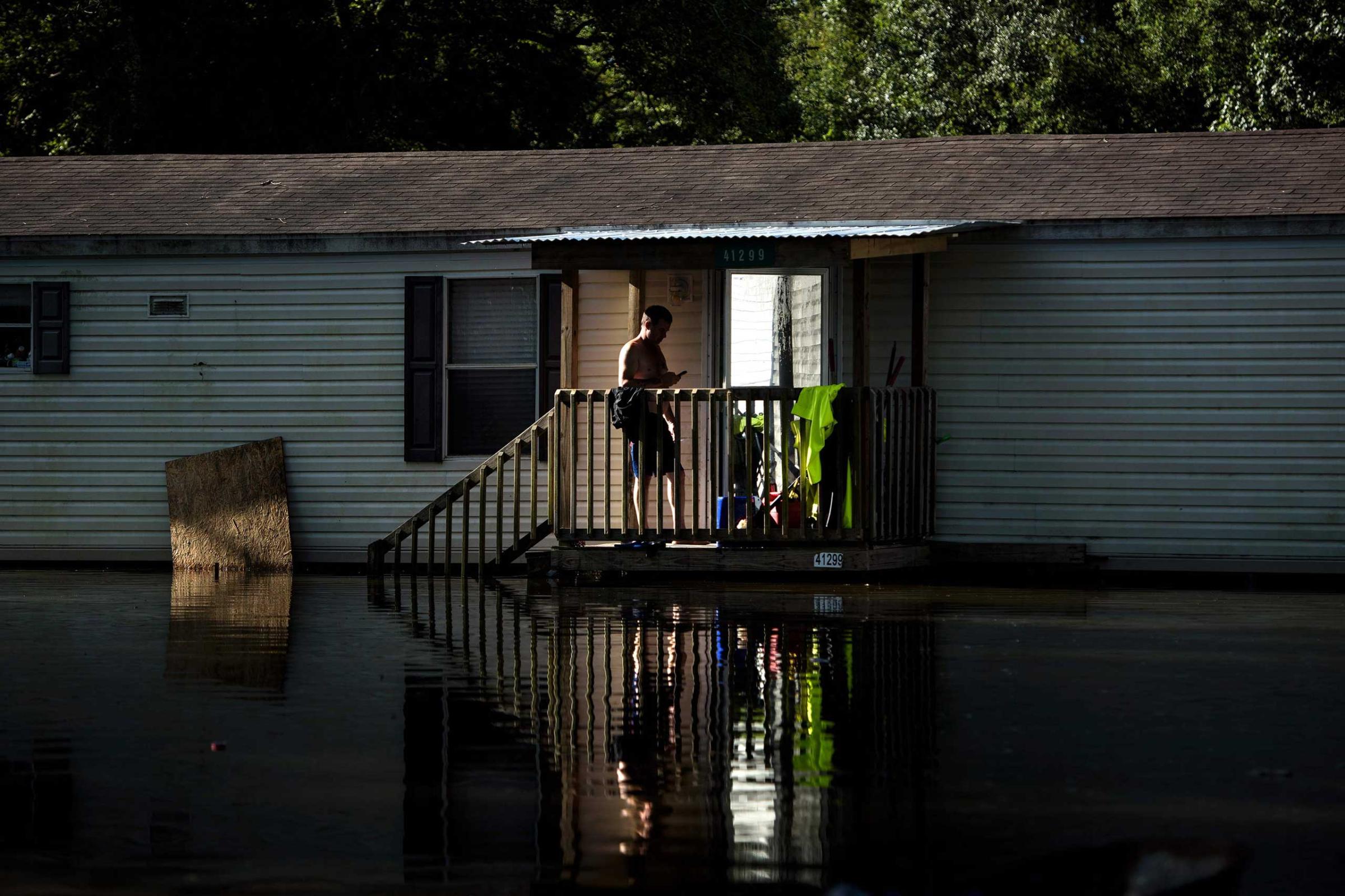 A man stands on the stairs os a home surrounded by floodwaters in Gonzales, La., on Aug. 16, 2016.