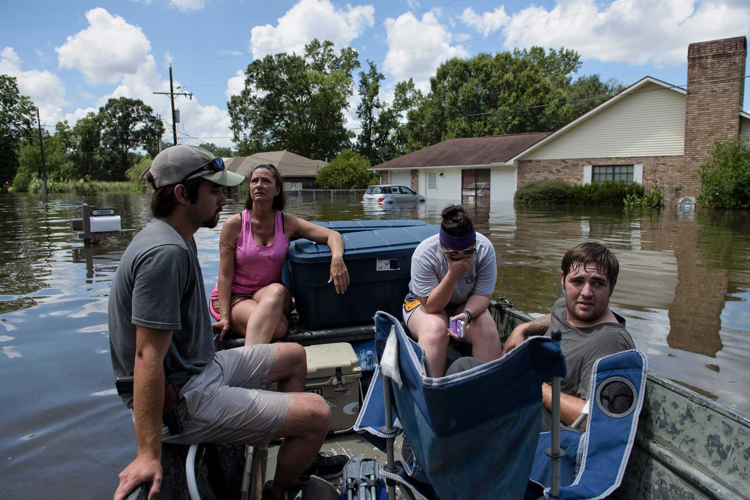 John Booth, left, sits with Angela Latiolais's family while helping them save belongings after flooding in Gonzales, La., on Aug. 16, 2016.