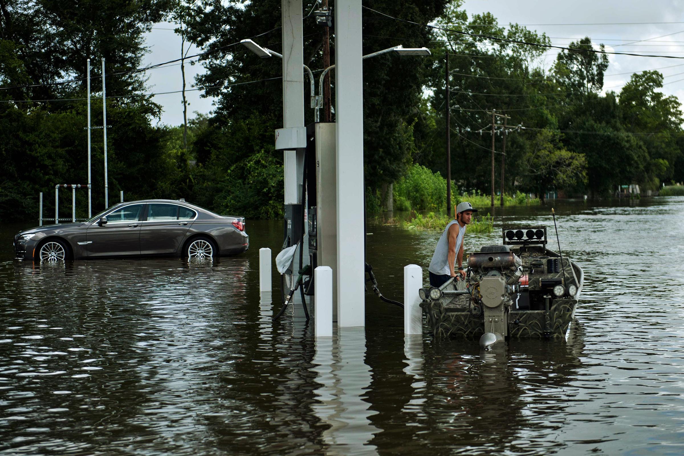 A man waits at a gas station with a boat while helping to evacuate a neighborhood after flooding in Gonzales, La., on Aug. 16, 2016.