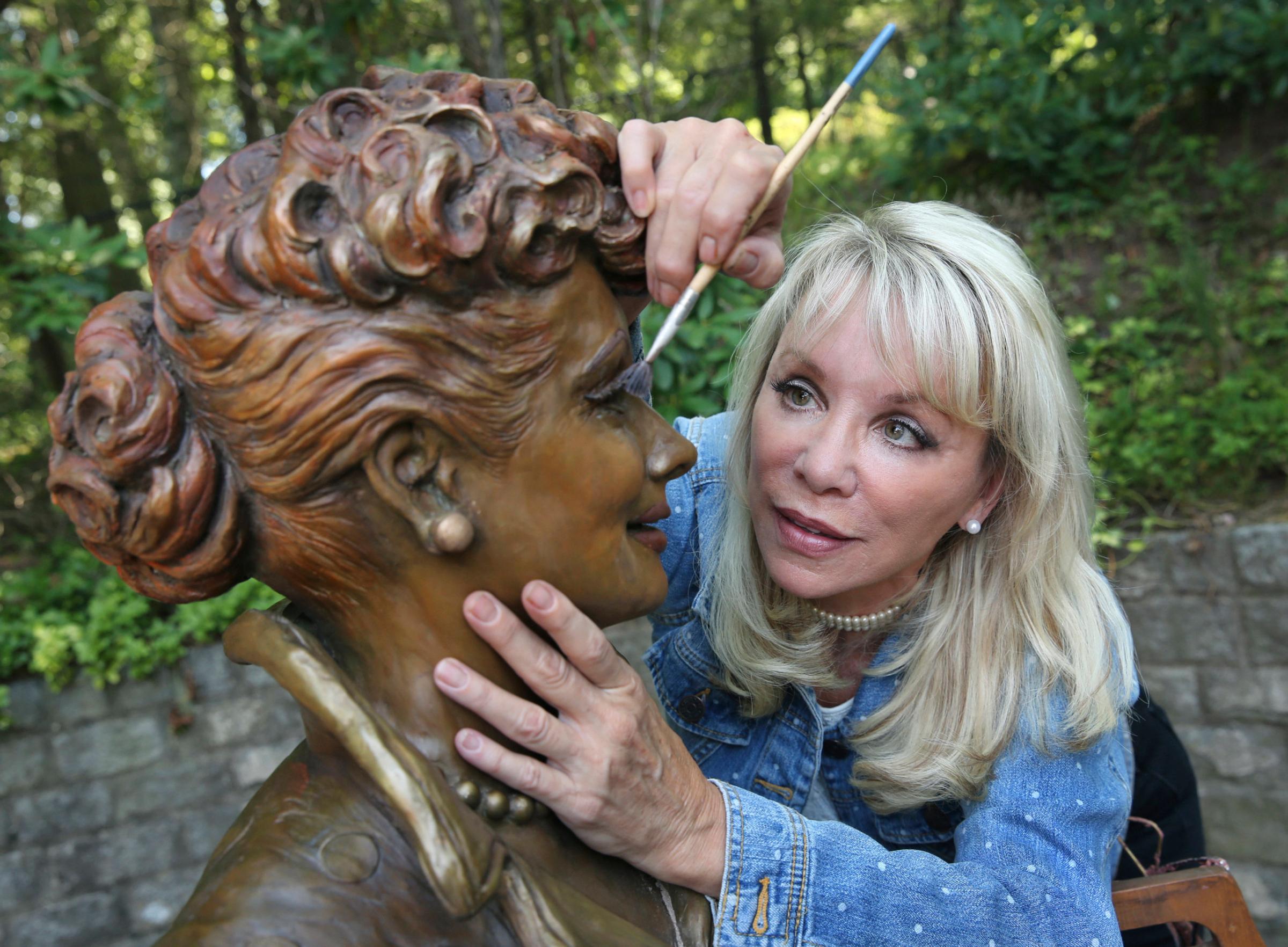 In this Wednesday, July 20, 2016 photo, artist Carolyn Palmer prepares to apply a cold patina to her bronze statue of Lucille Ball in Saddle River, N.J. The sculptor was chosen to create a replacement statue for one dubbed "Scary Lucy," in the late actress Ball's hometown. The much-maligned statue of Ball will be replaced after it drew worldwide attention as "Scary Lucy," according to the mayor of the western New York village where the 1950s sitcom actress and comedian grew up and her life-size bronze has stood since 2009. (AP Photo/Mel Evans)