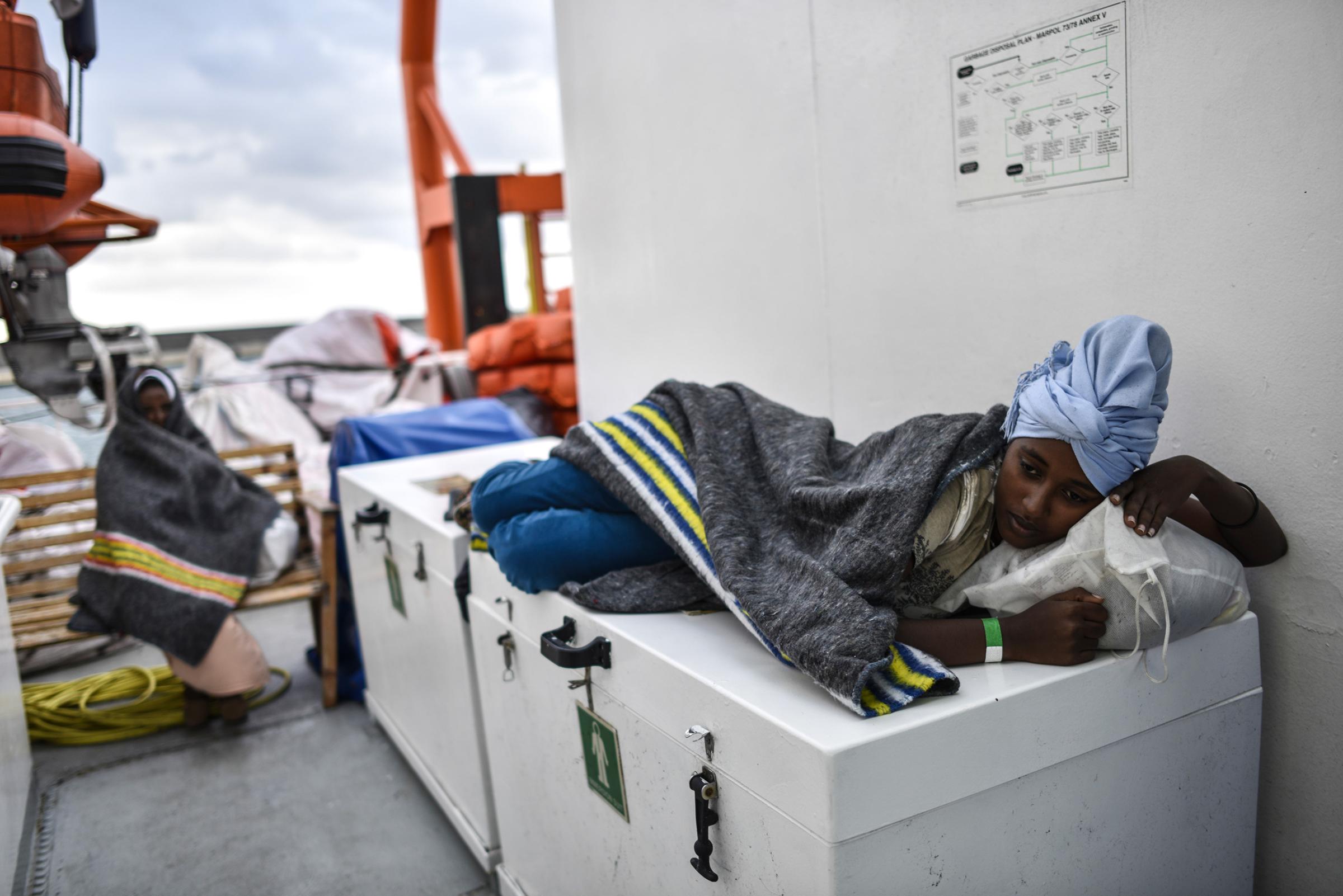 A young migrant woman rests on the deck as the ship sails to Italy, Aug. 23, 2016.