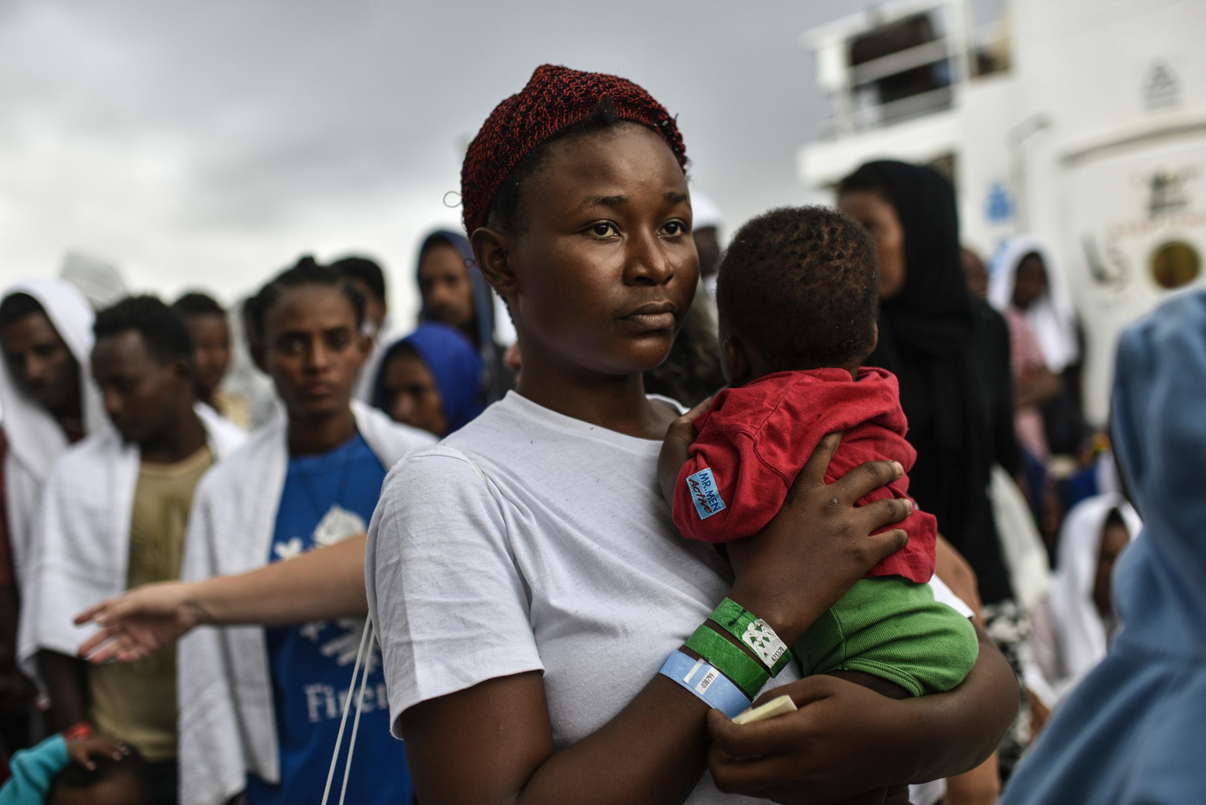 A Nigerian migrant, Goodness, age 20, holds her young daughter Destiny, as she waits to disembark at the Catania port, Sicily, Aug. 23, 2016.