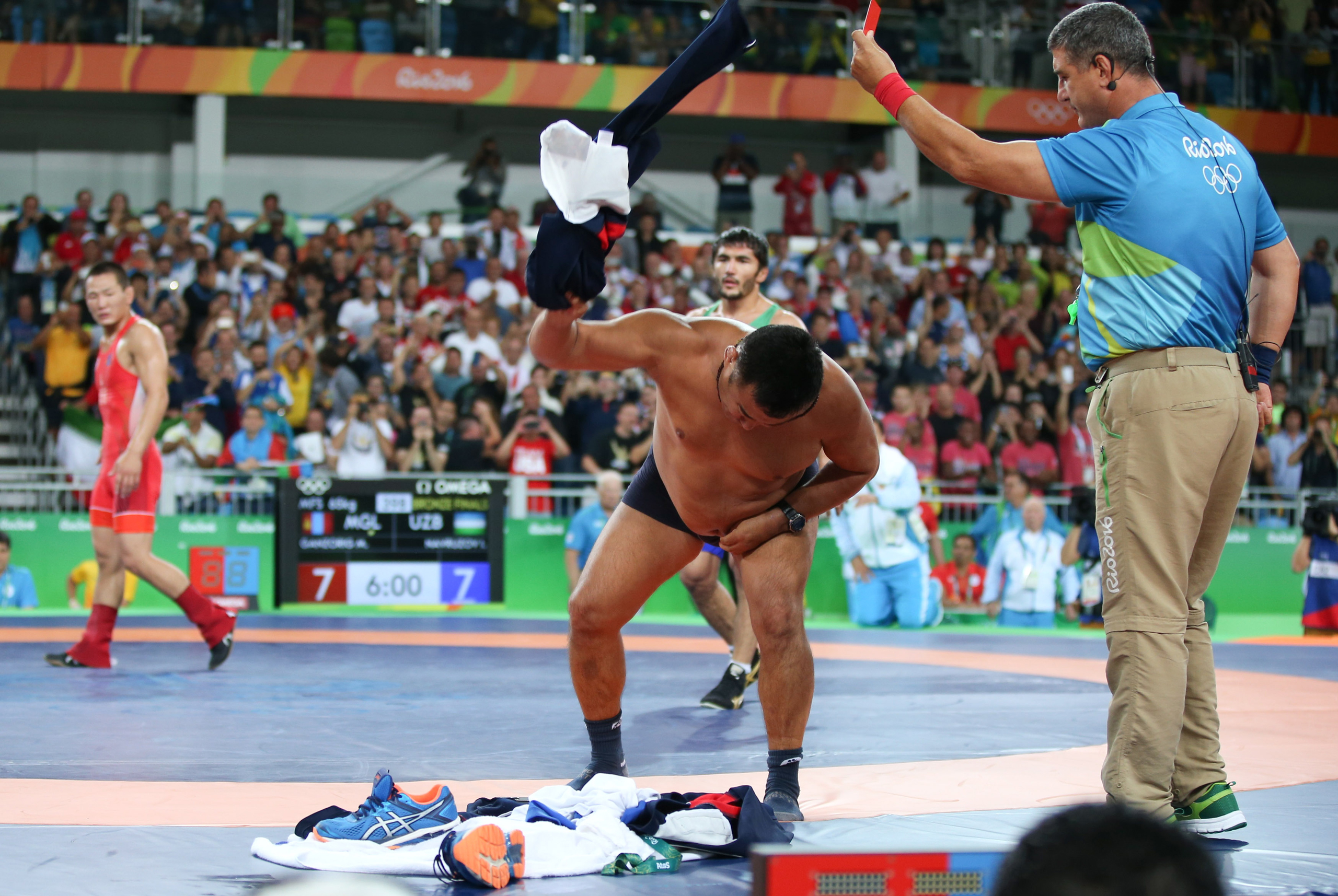 The coach of Mongolian wrestler Ganzorigiin Mandakhnaran takes off his clothes as he protests after the men's freestyle 65-kg bronze-medal match against Ikhtiyor Navruzov of Uzbekistan at the Olympic Games on Aug. 21, 2016 (Toru Hanai—Reuters)