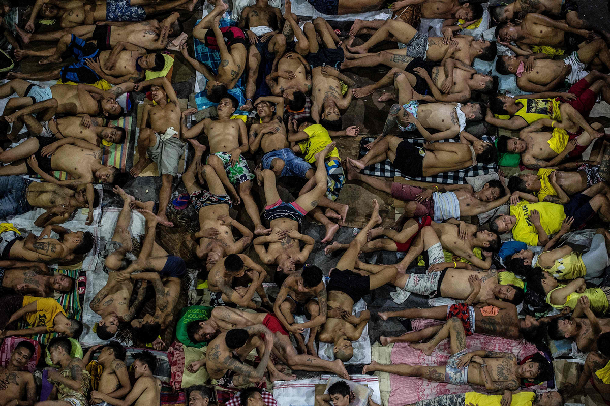 Inmates sleep on the ground of an open basketball court inside the Quezon City Jail at night in Manila, Philippines, on July 19, 2016. There are 3,800 inmates at the jail, which was built six decades ago to house 800. (Noel Celis—AFP/Getty Images)