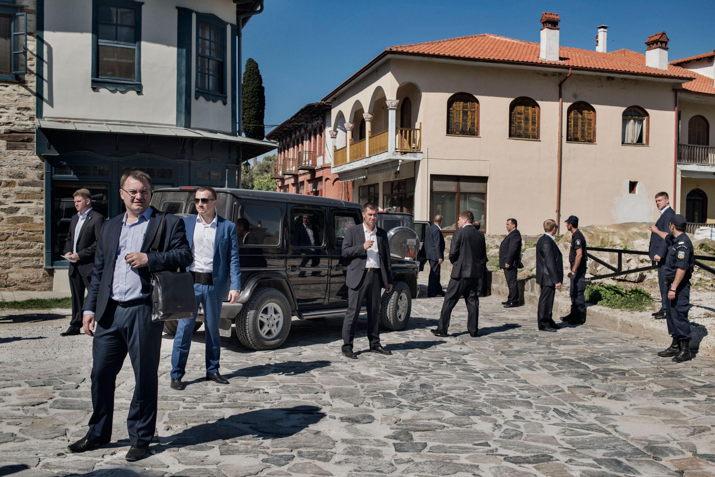 Russian secret service agents and Greek police officers surround a black Mercedes SUV carrying Russian President Vladimir Putin as he arrives in Karyes, the capital of Mount Athos, a self-governing community of Orthodox Christian monks in northern Greece, May 28, 2016.