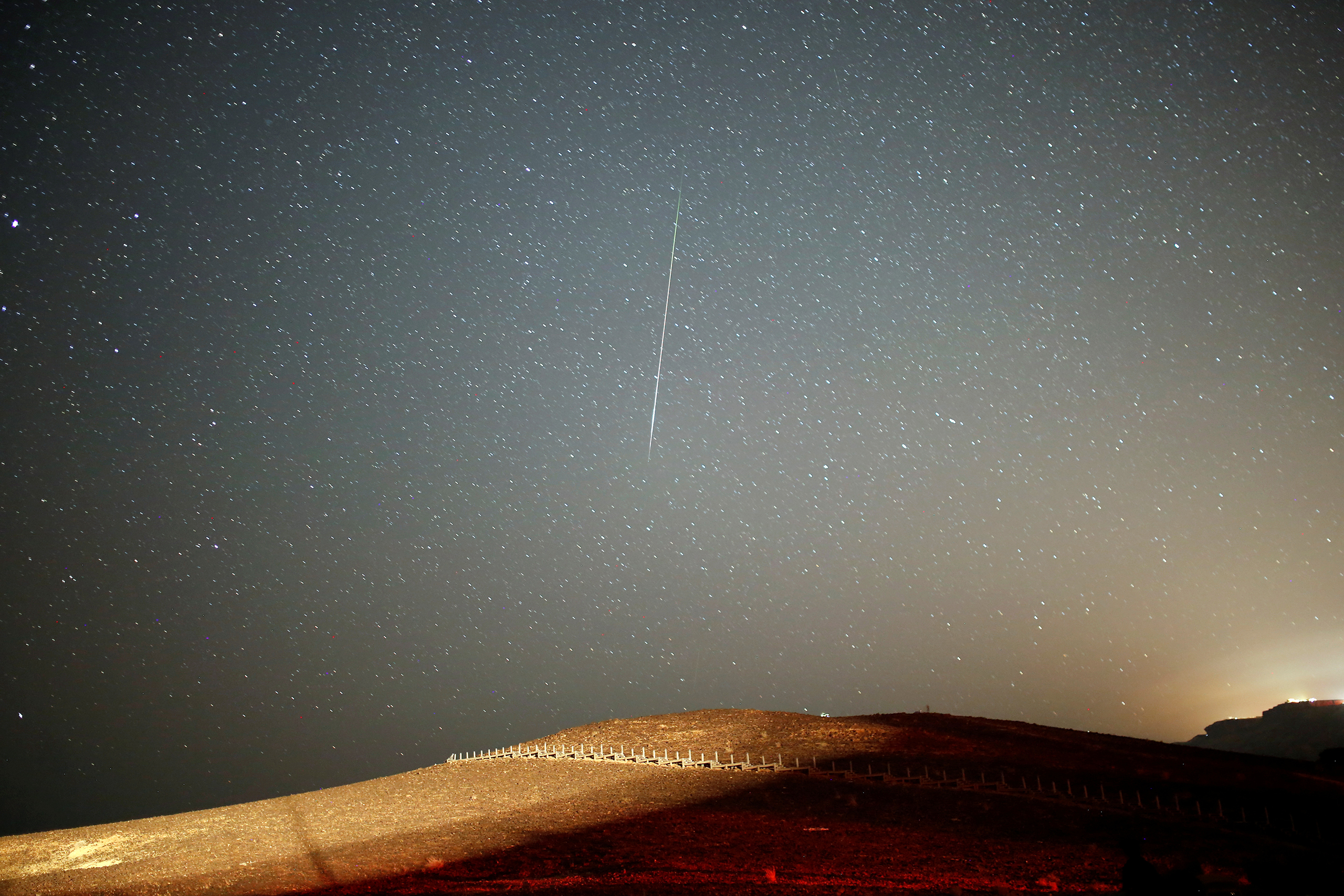 A meteor streaks across the sky in the early morning during the Perseid meteor shower in Ramon Crater near the town of Mitzpe Ramon, southern Israel, Aug. 12, 2016.