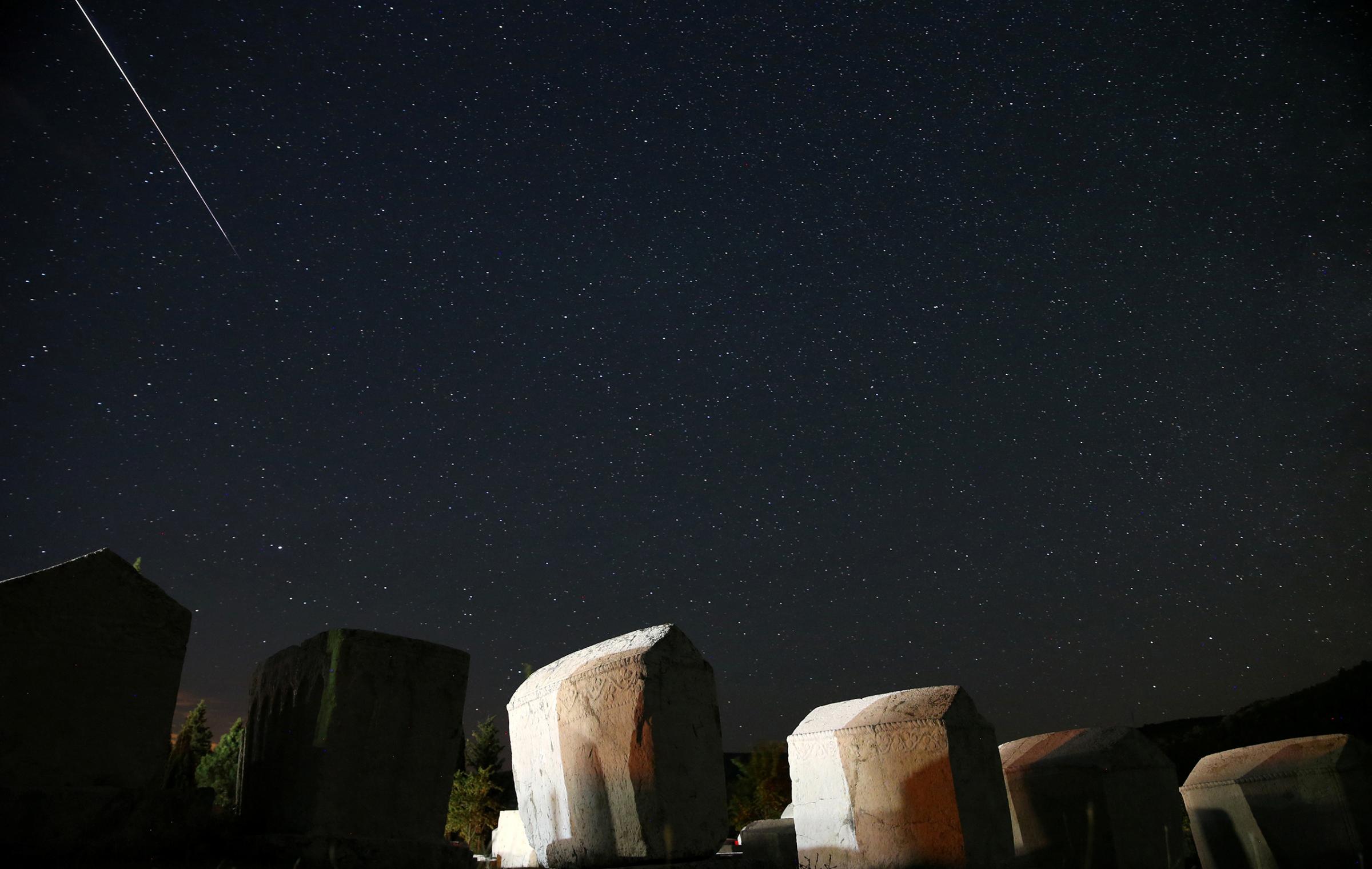 A meteor streaks past stars in the night sky above medieval tombstones in Radmilje near Stolac, south of Sarajevo, Bosnia and Herzegovina, Aug. 12, 2016.