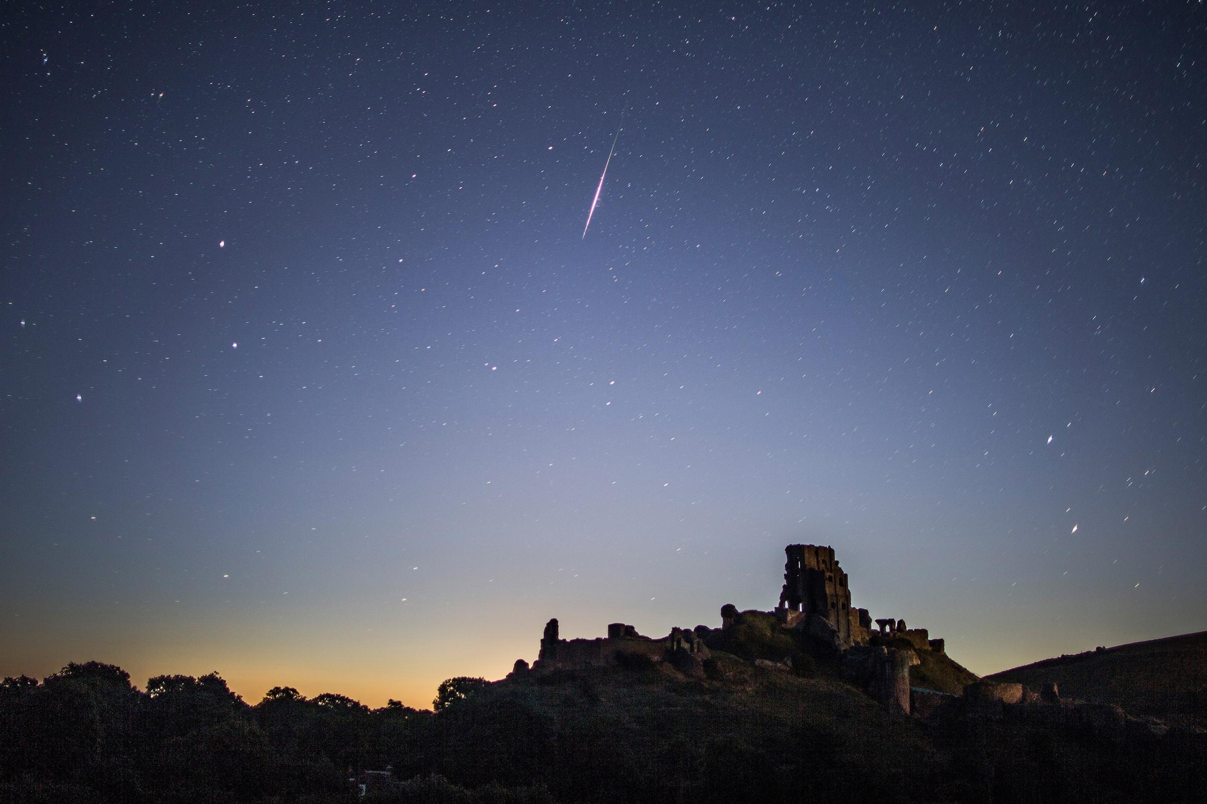 A Perseid meteor flashes across the night sky above Corfe Castle, United Kingdom, on Aug. 12, 2016.