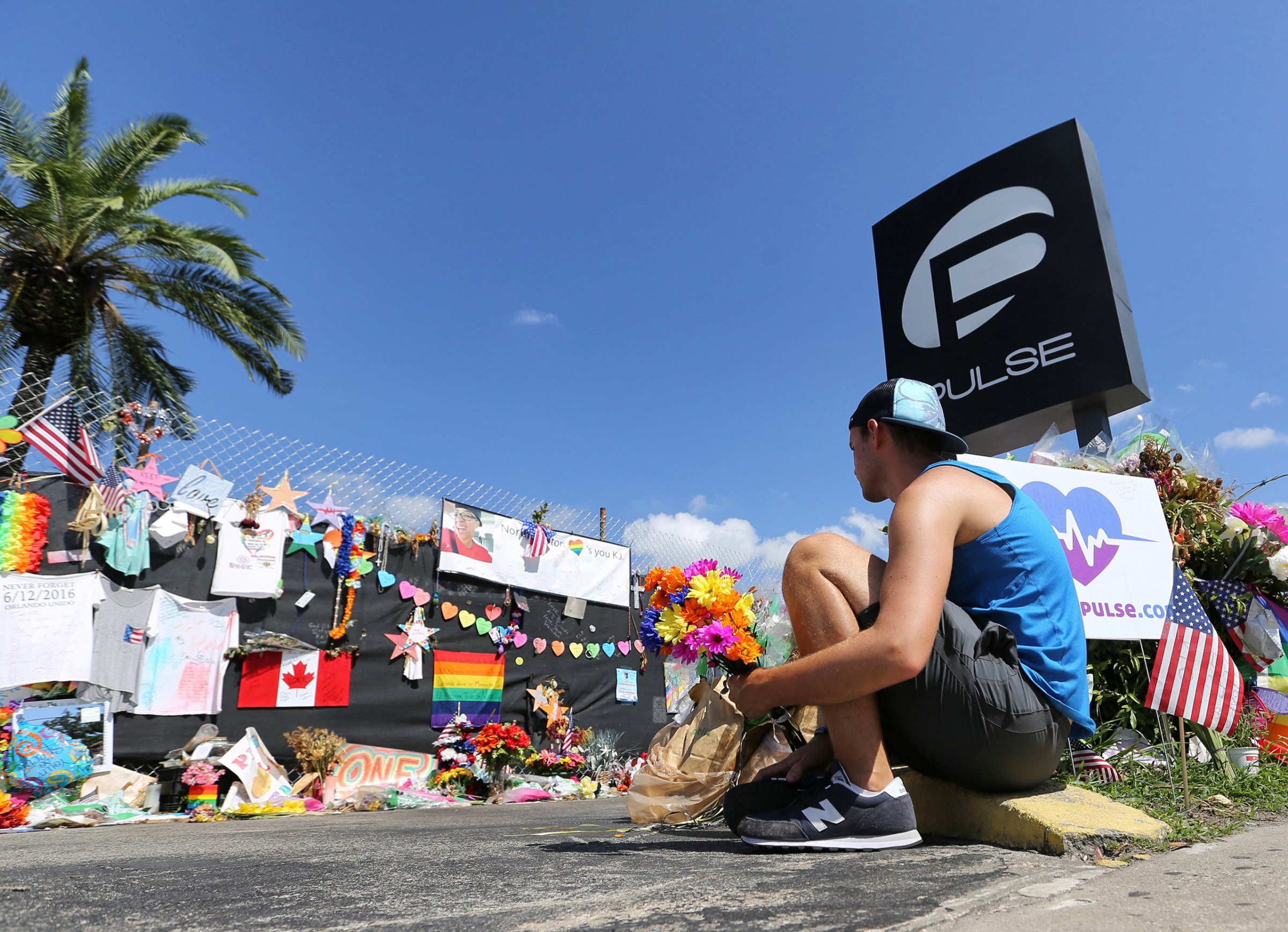 On the eve of the one-month anniversary of the Pulse nightclub massacre, a friend of two of the victims places flowers as visitors continue to flock to the club to their pay their respectsin Orlando on July 11, 2016.